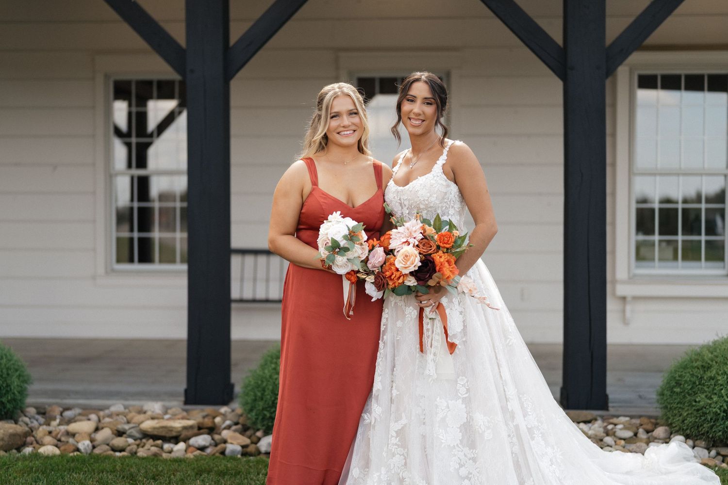 Wedding party members in red and white dresses pose together outdoors.
