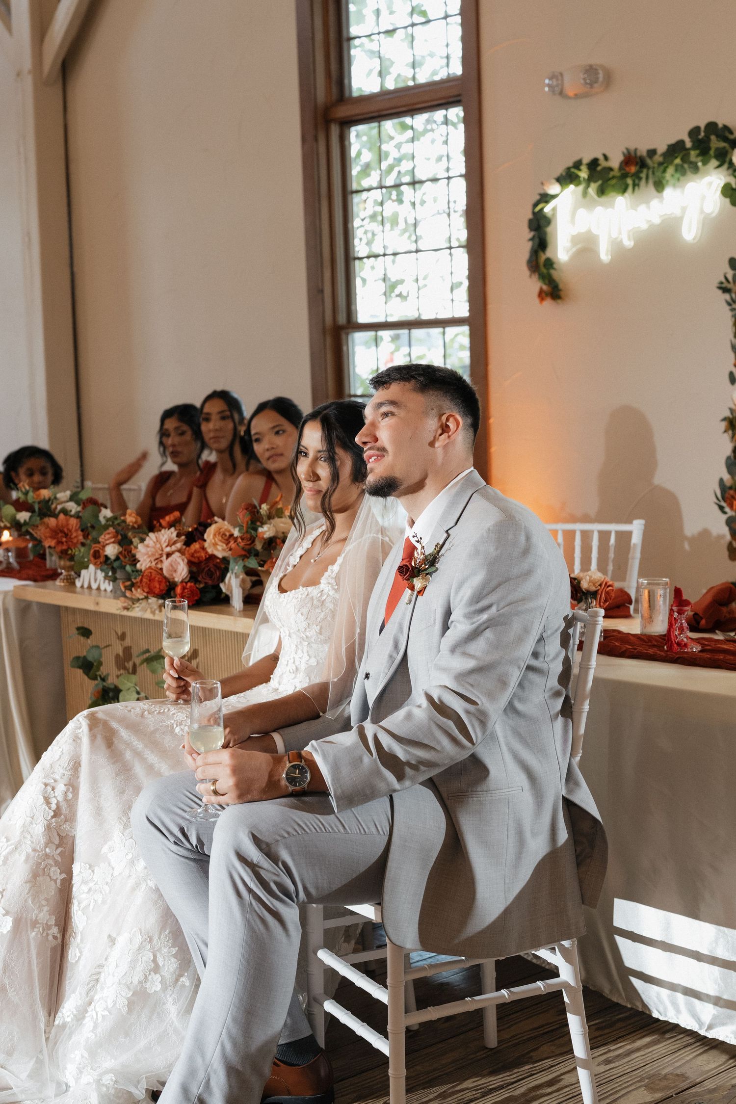 Wedding reception scene in elegant white room with stained glass windows and decorative lighting.