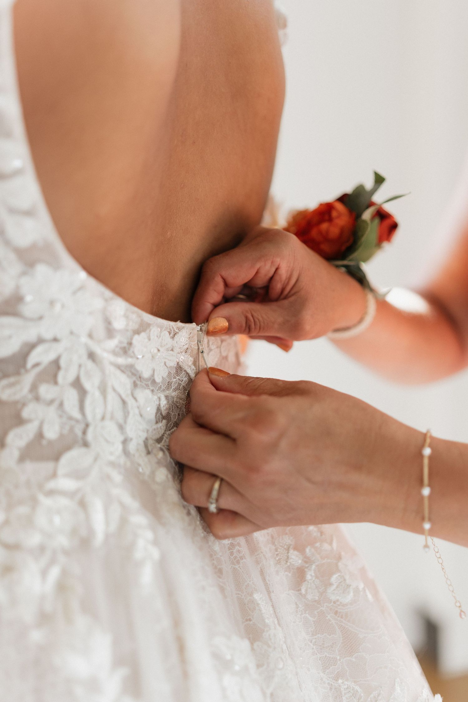 Close-up details of a white lace wedding dress being fastened.