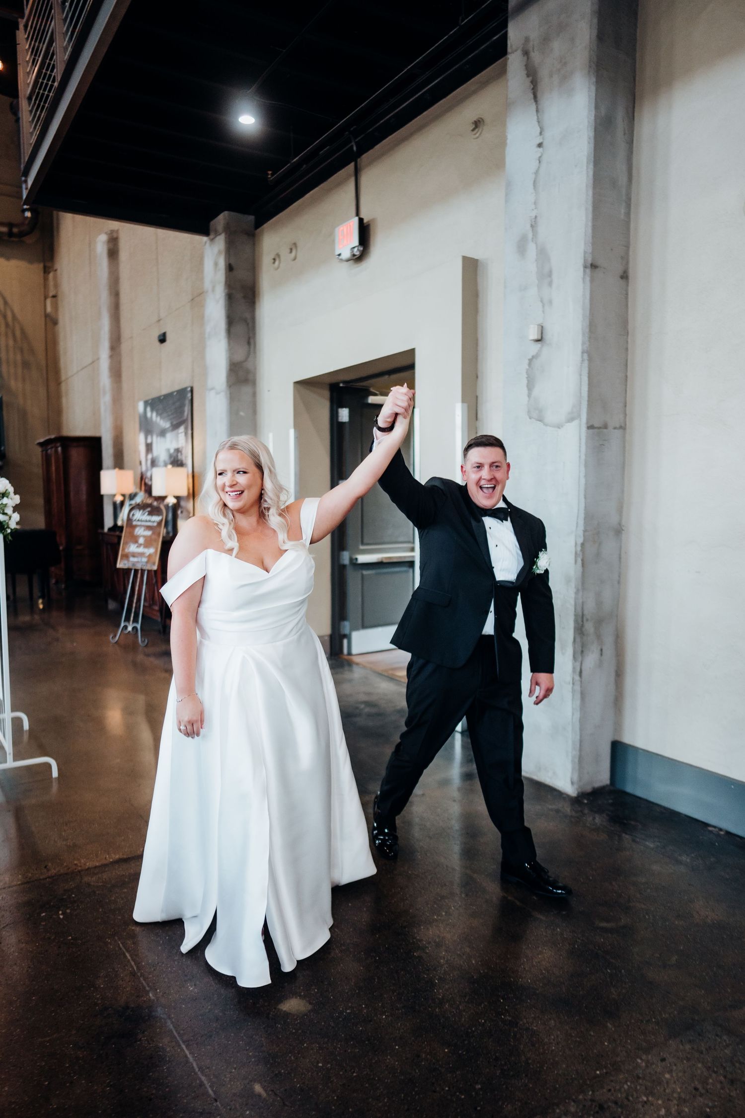 Joyful dancing and celebration in an industrial-style wedding venue with concrete pillars.