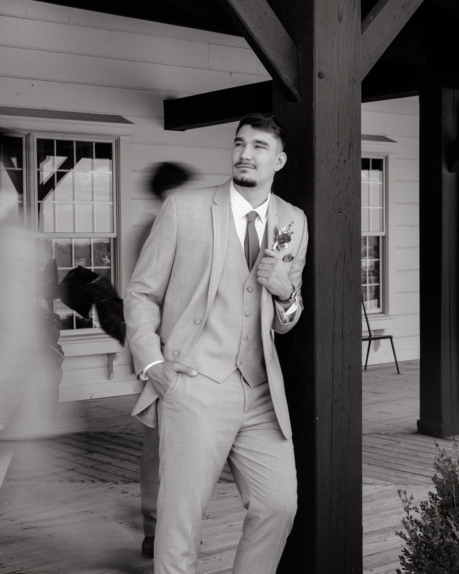 A series of black and white photos showing a groom in a light colored suit on a covered porch.