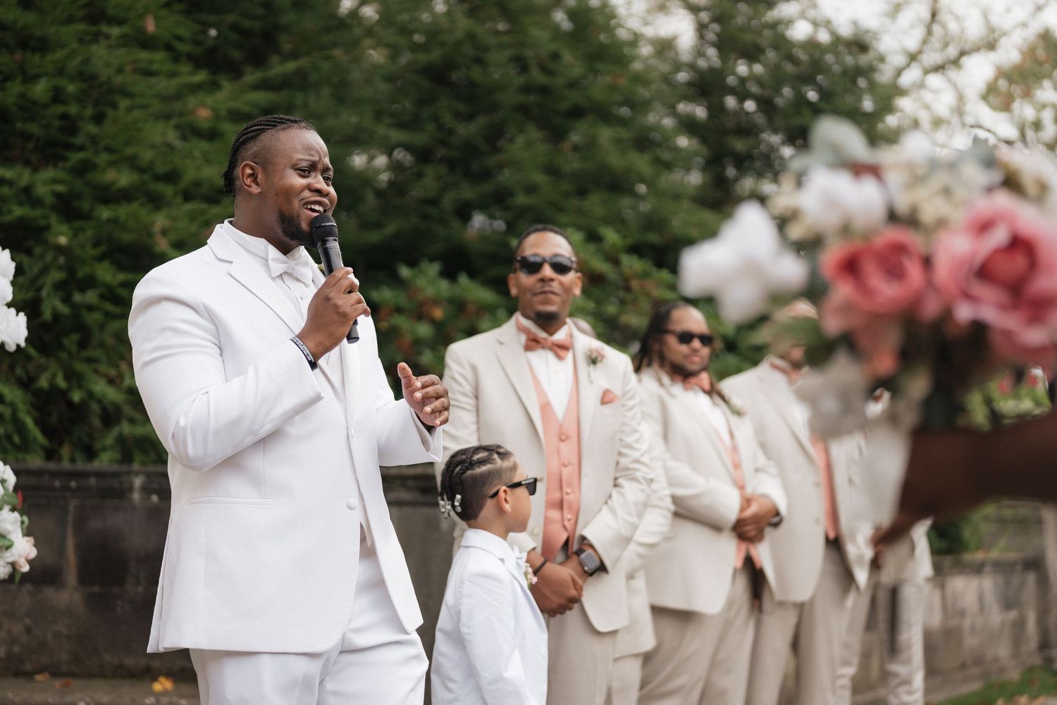 Wedding party in white attire celebrates joyfully outdoors.