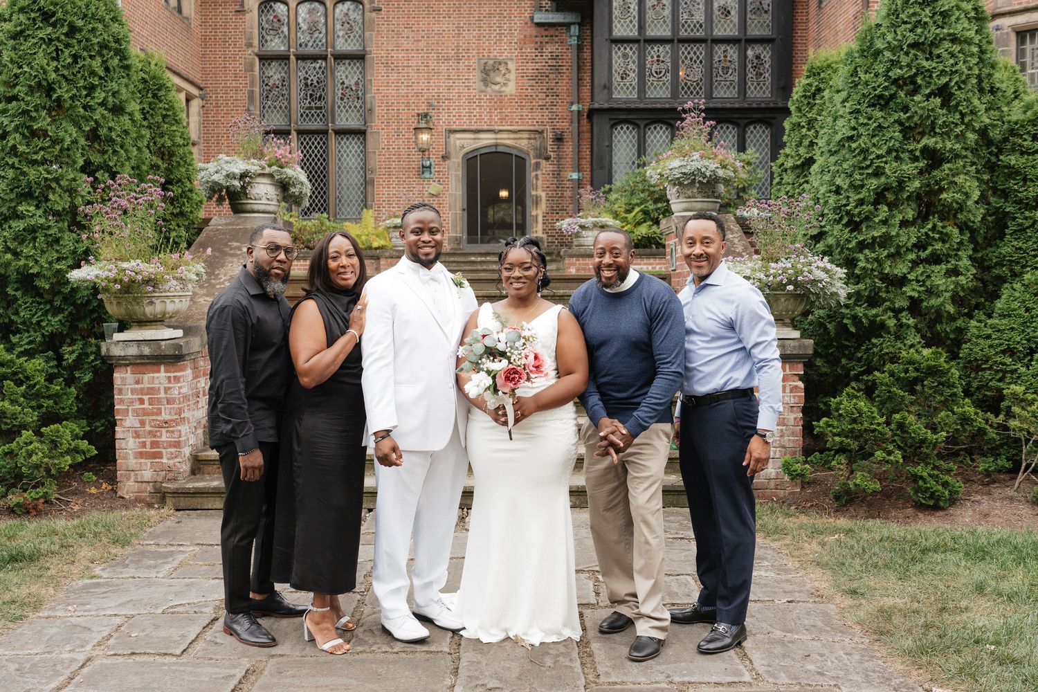 Wedding party poses outside historic brick building with ivy covered walls.