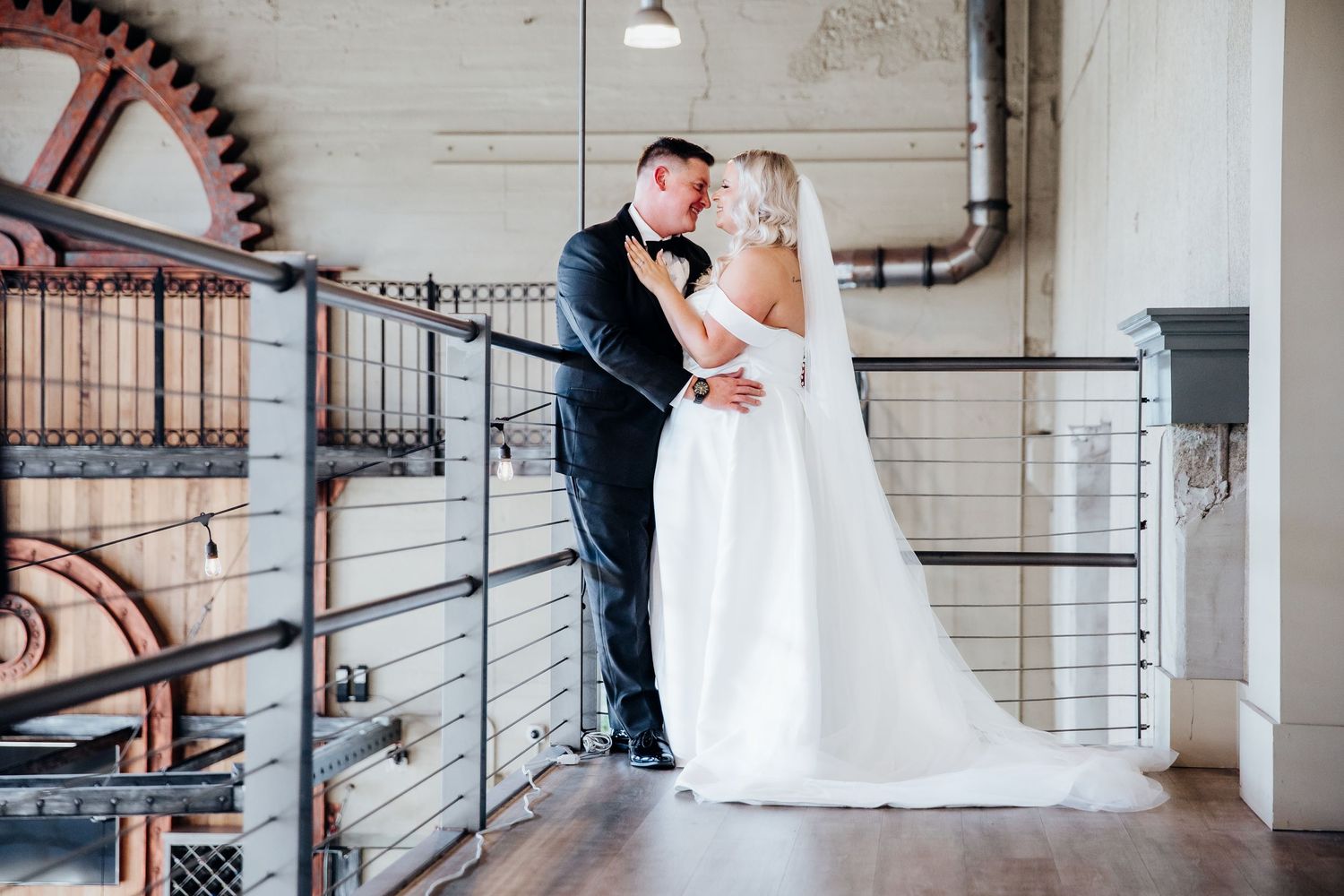 Wedding couple poses in romantic shots along an industrial-style balcony with metal railings.