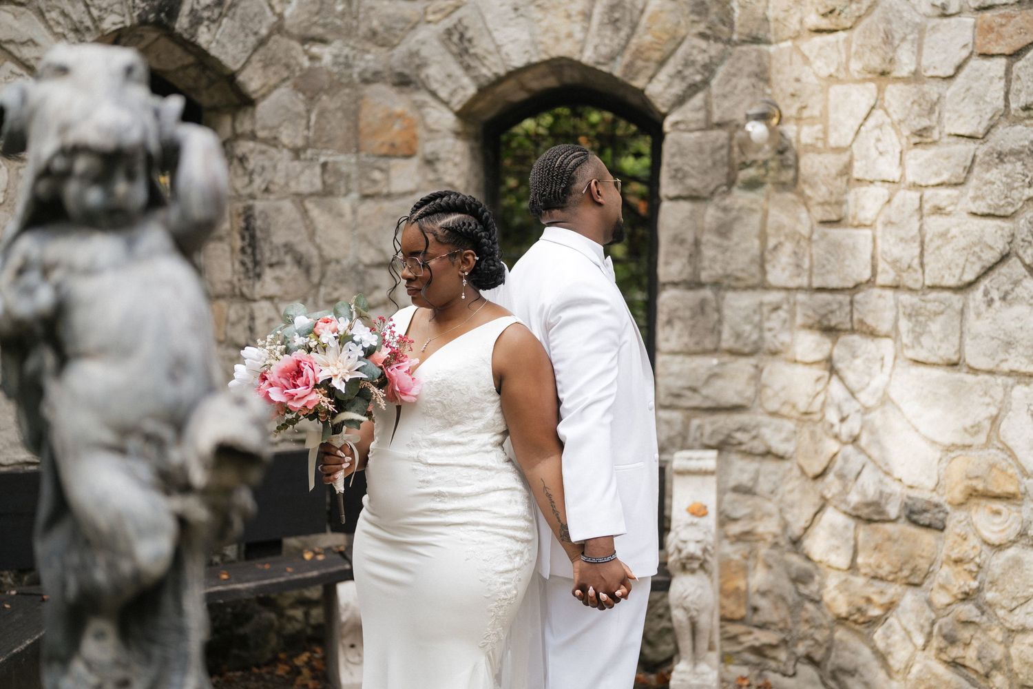 Wedding couple shares intimate moment against rustic stone wall backdrop.