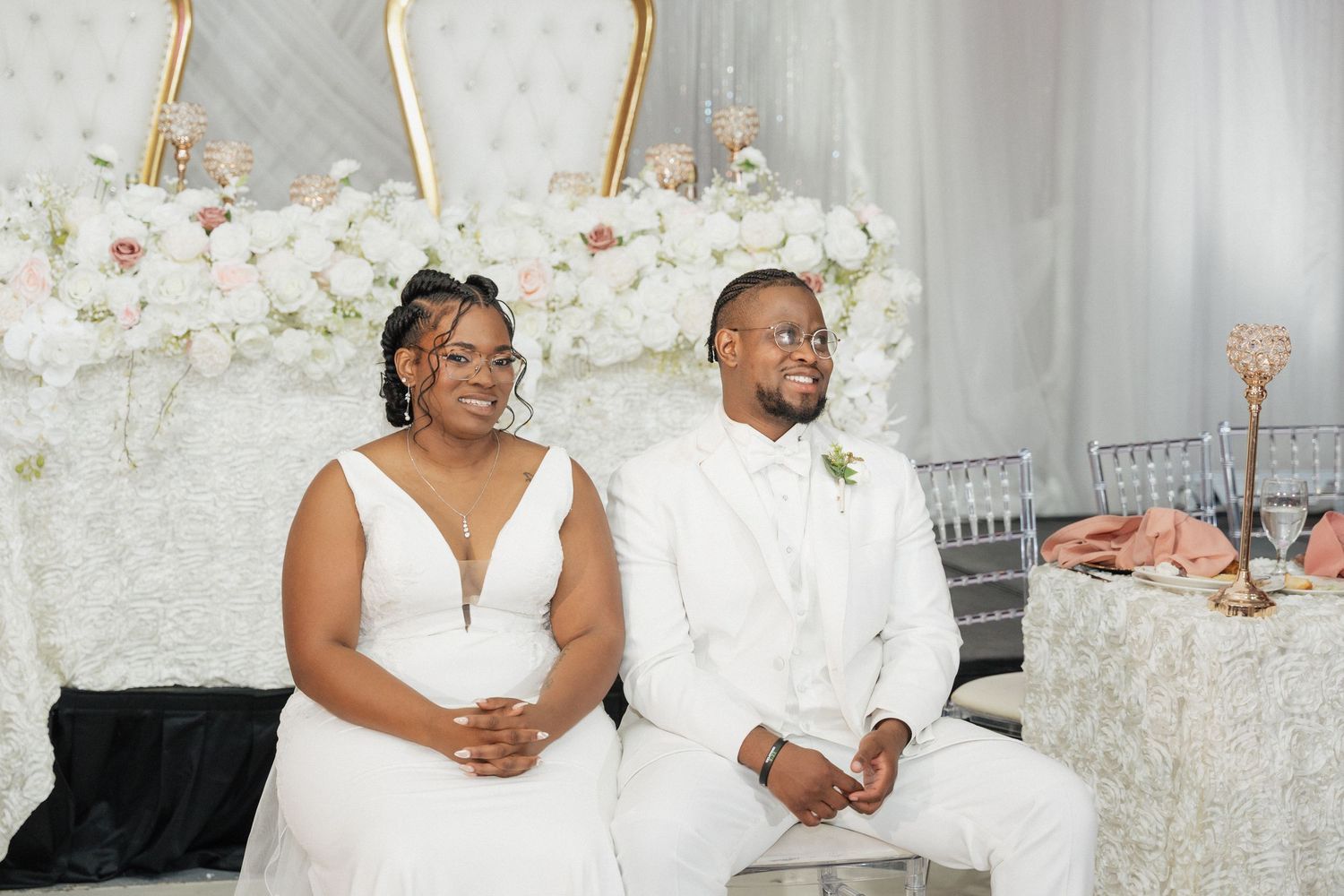 Wedding couple and guests celebrate at elegant reception with floral wall backdrop.