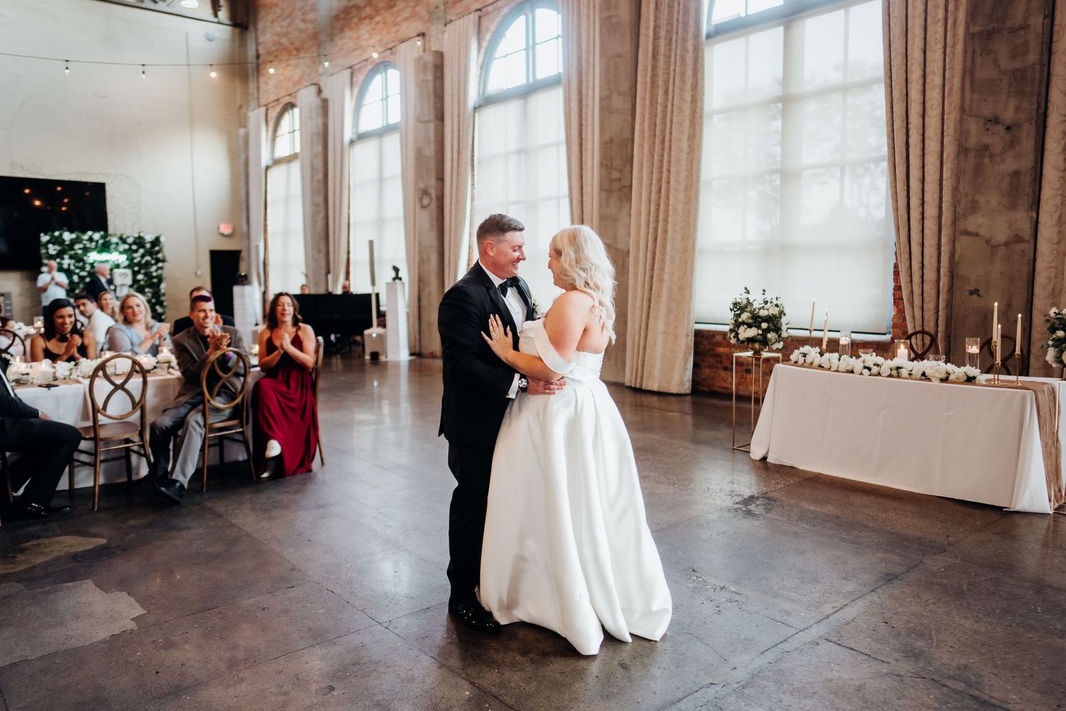 Wide angle view of a wedding ceremony in a modern industrial space with exposed brick walls.