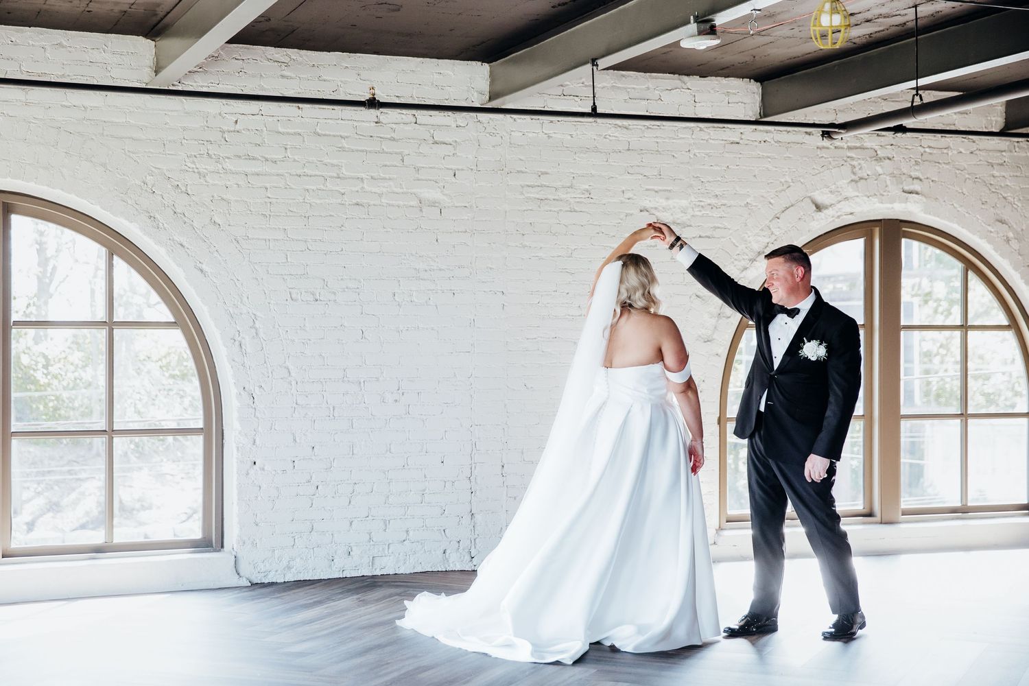 Wedding couple sharing a moment in an industrial-style venue with white brick walls.