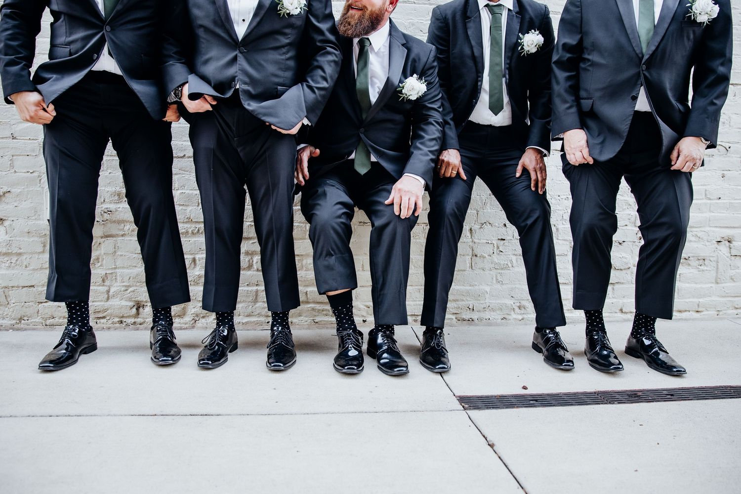 Groomsmen show off their matching suits and dress shoes in stylish wedding photo.