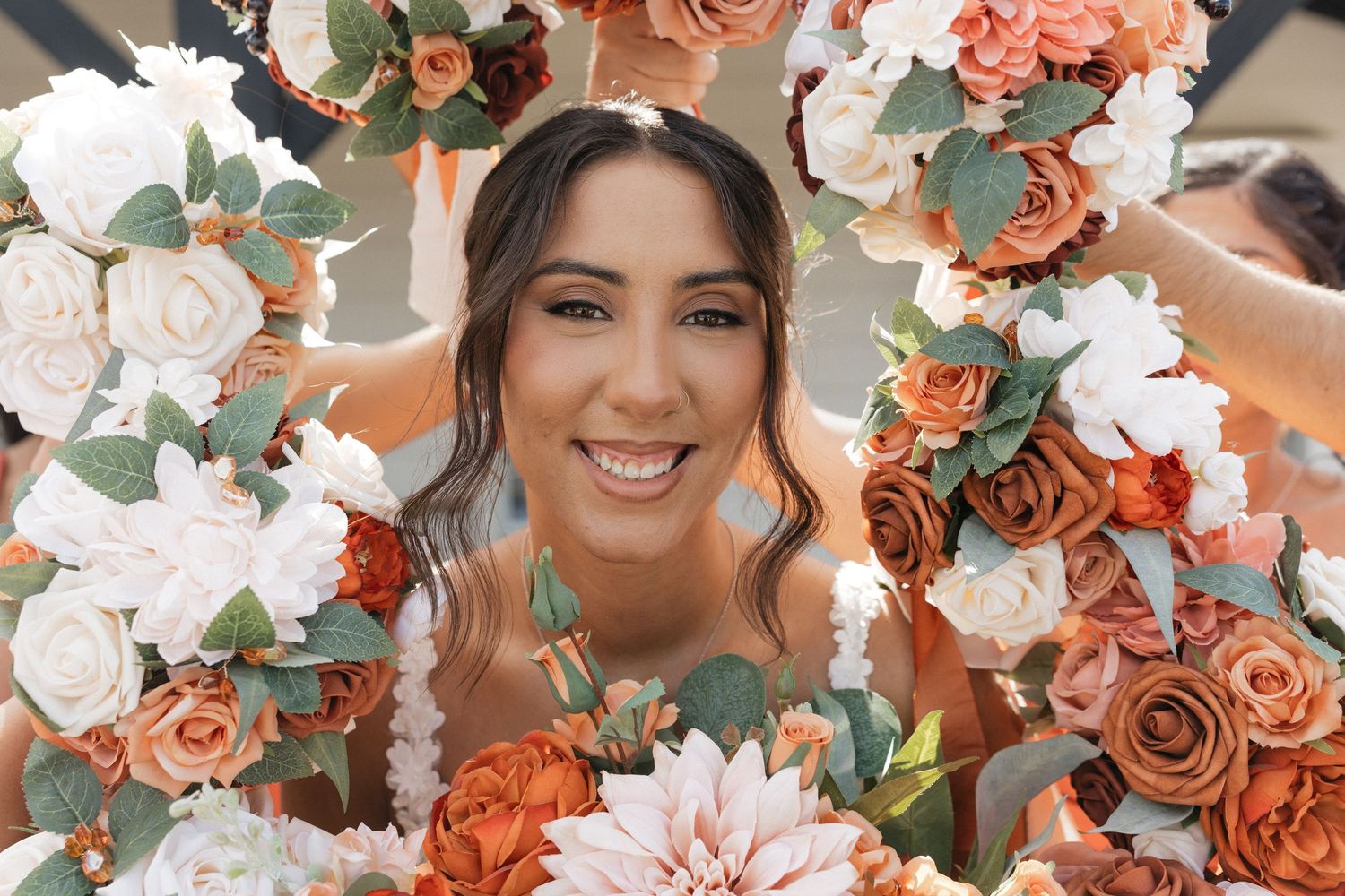 Beautiful wedding bouquet featuring coral, peach and white roses with greenery.