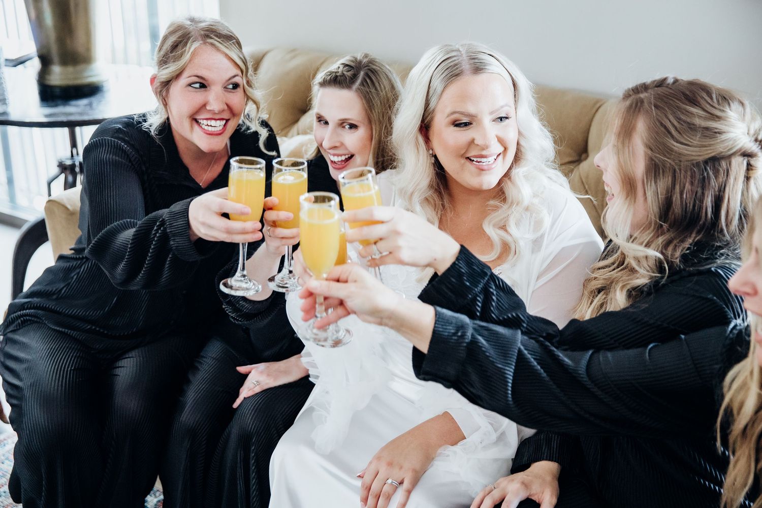 Wedding party members toast with drinks while celebrating together.
