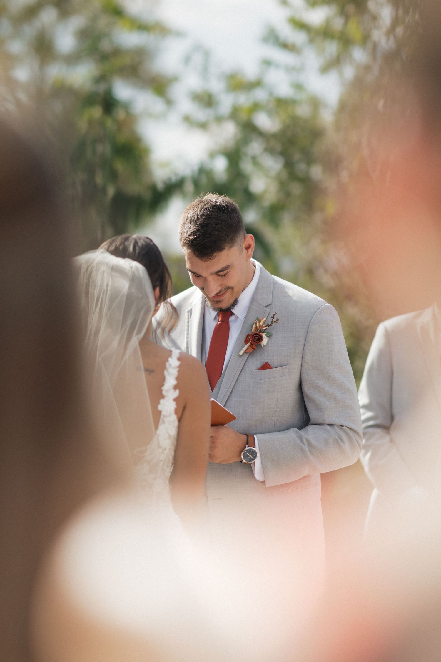 Intimate wedding ceremony moment captured through soft focus with gray and white attire.
