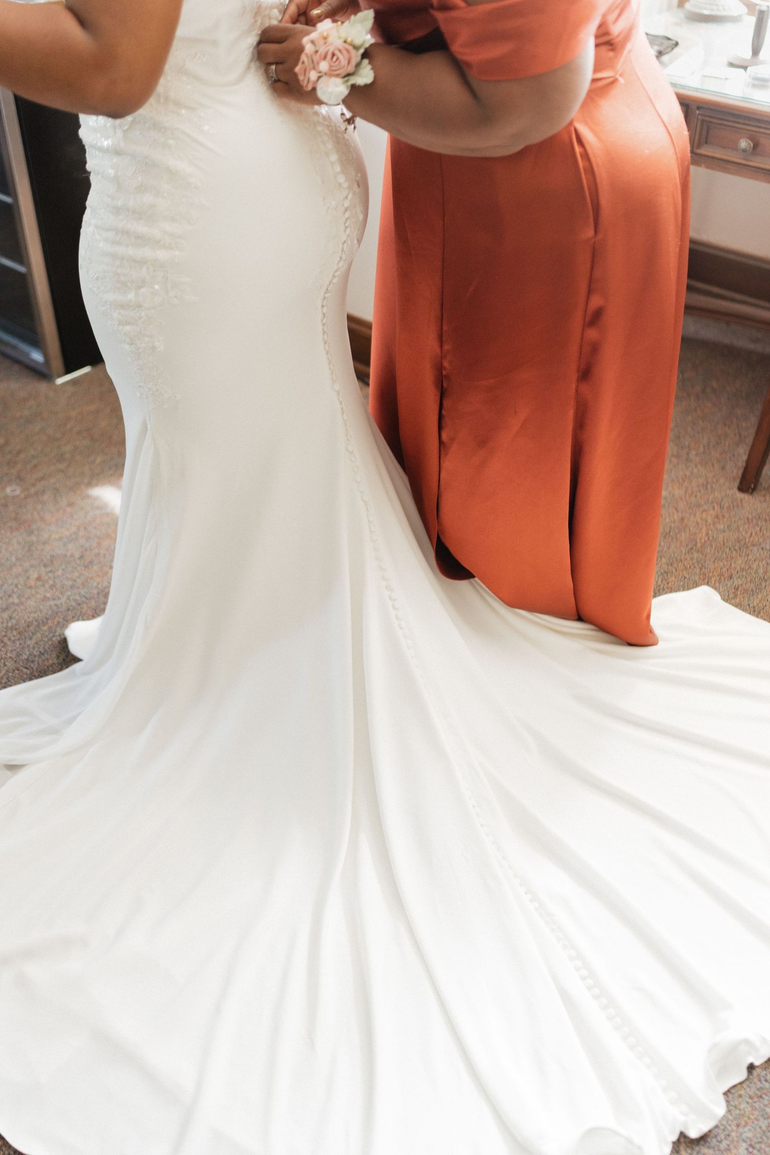 Close-up view of a flowing white wedding dress train with coral-colored accents.
