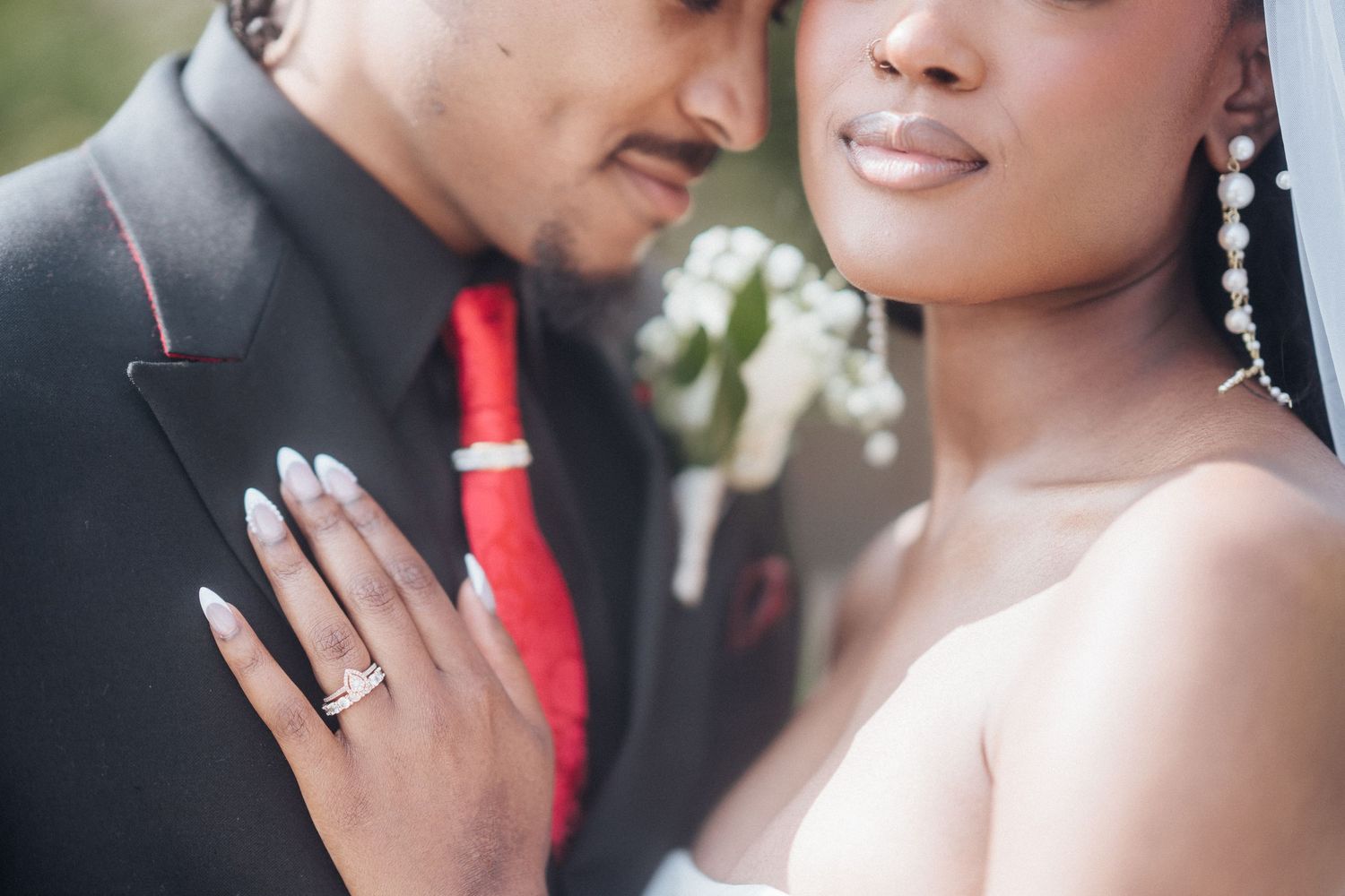 Elegant wedding photo showing jewelry and formal attire details in soft natural lighting.