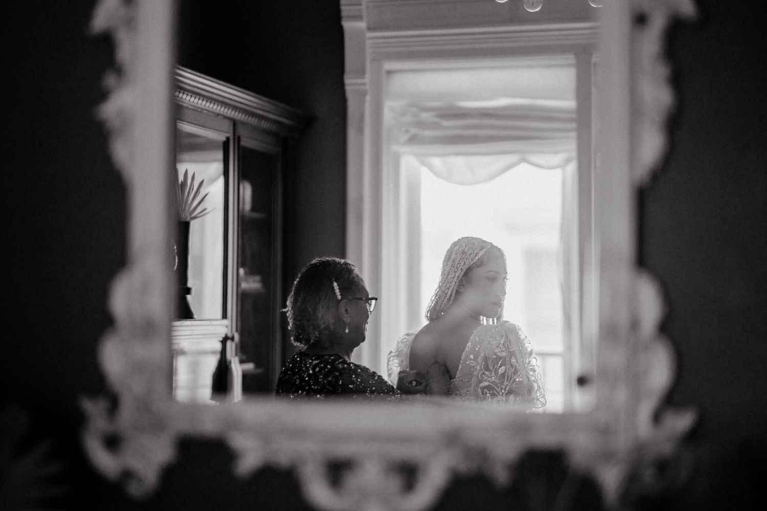 Artistic black and white mirror reflection of wedding preparation scene.