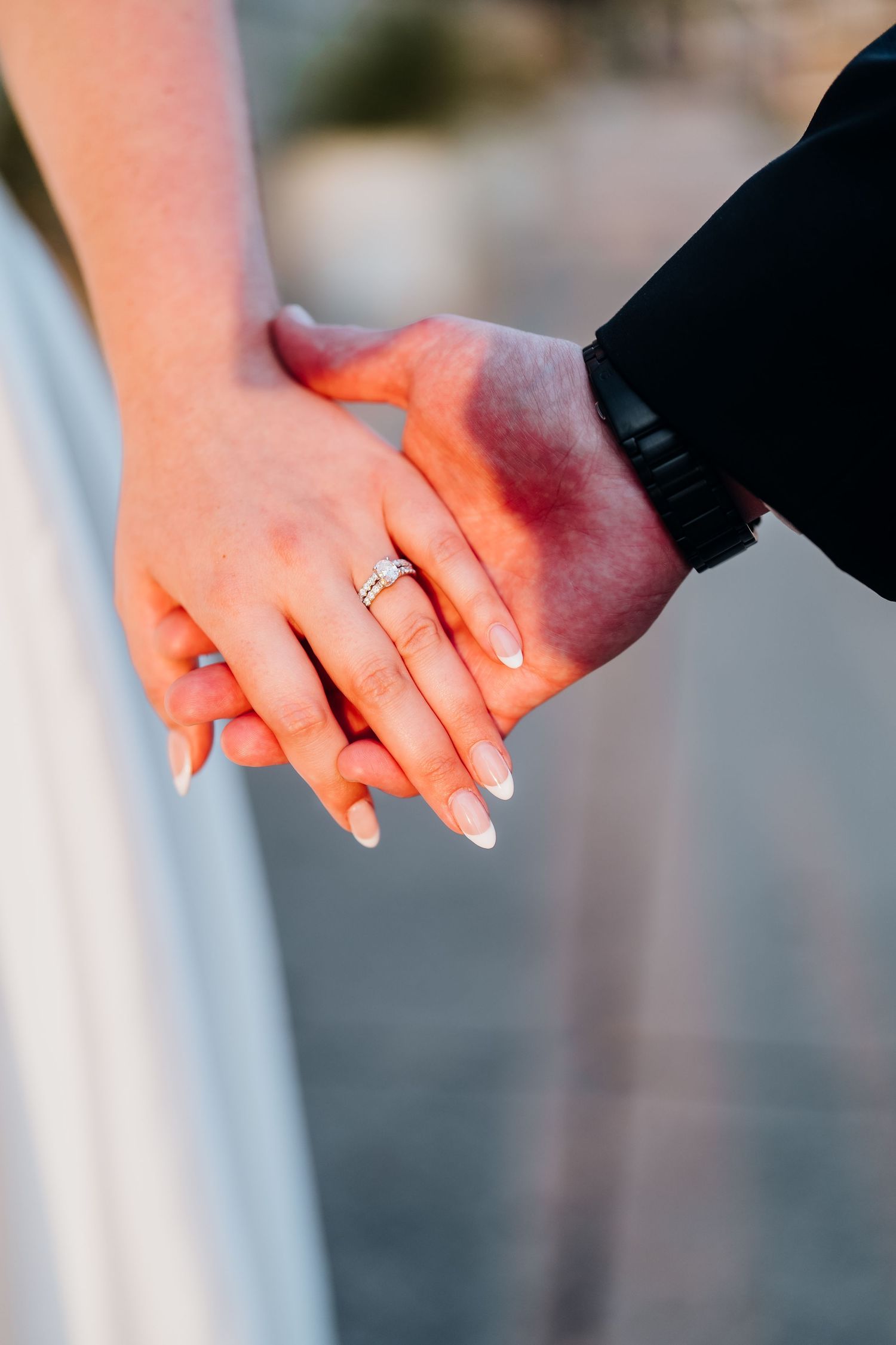Close-up of newlywed couple holding hands showing wedding ring.
