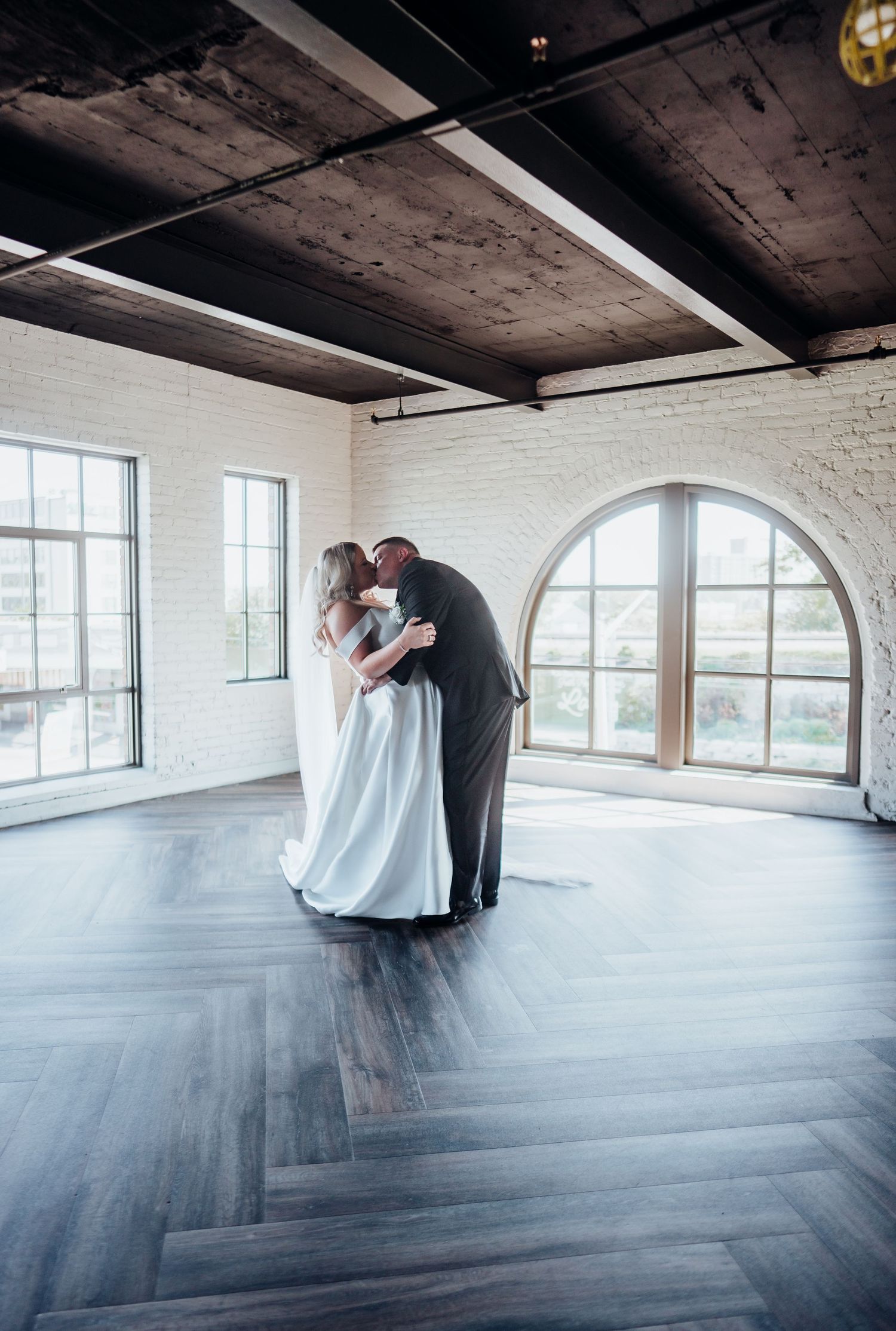 Series of romantic dance moments captured in a bright industrial venue with arched windows.