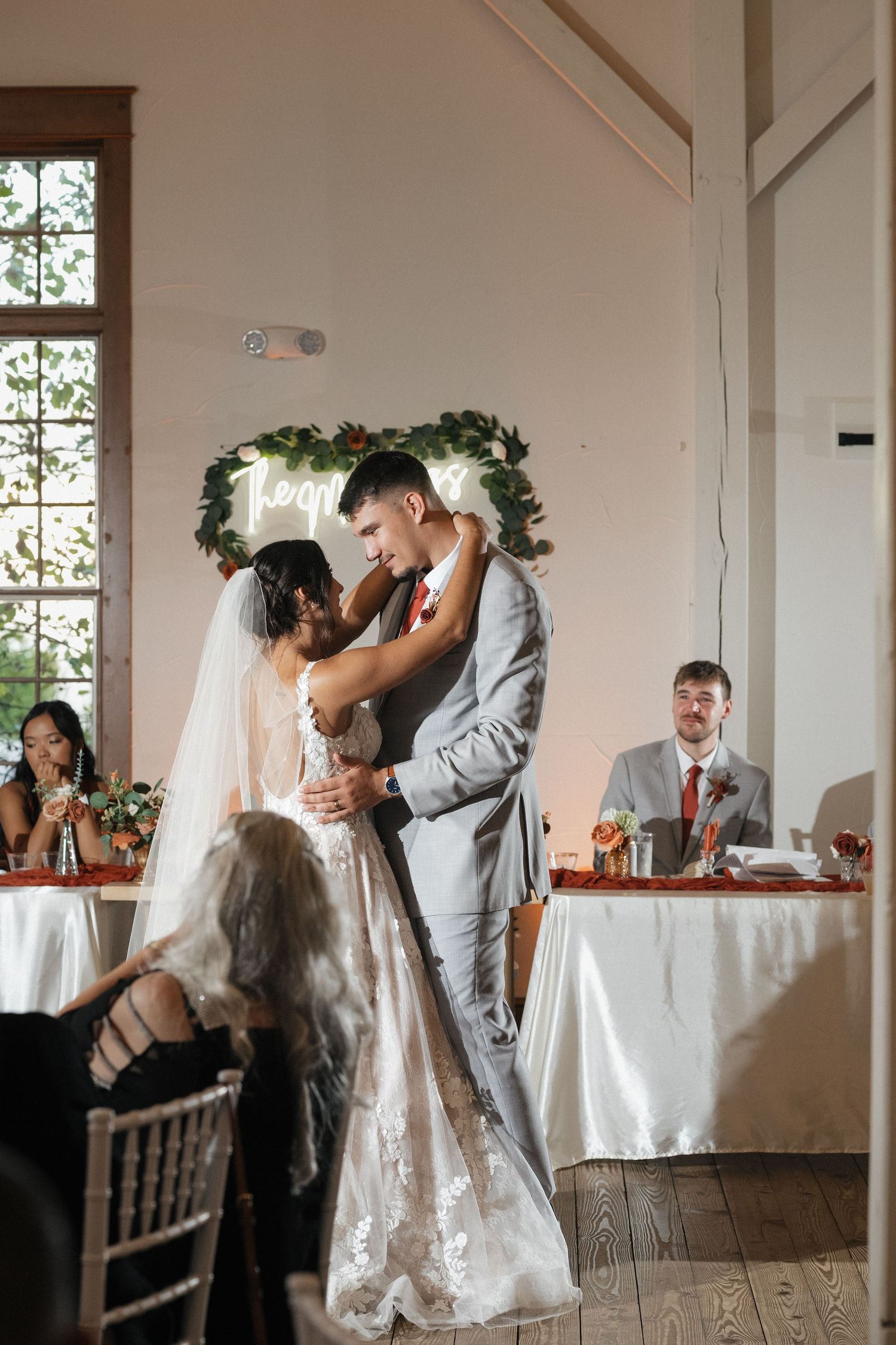First dance moments captured in a bright indoor venue with white walls and wooden floors.