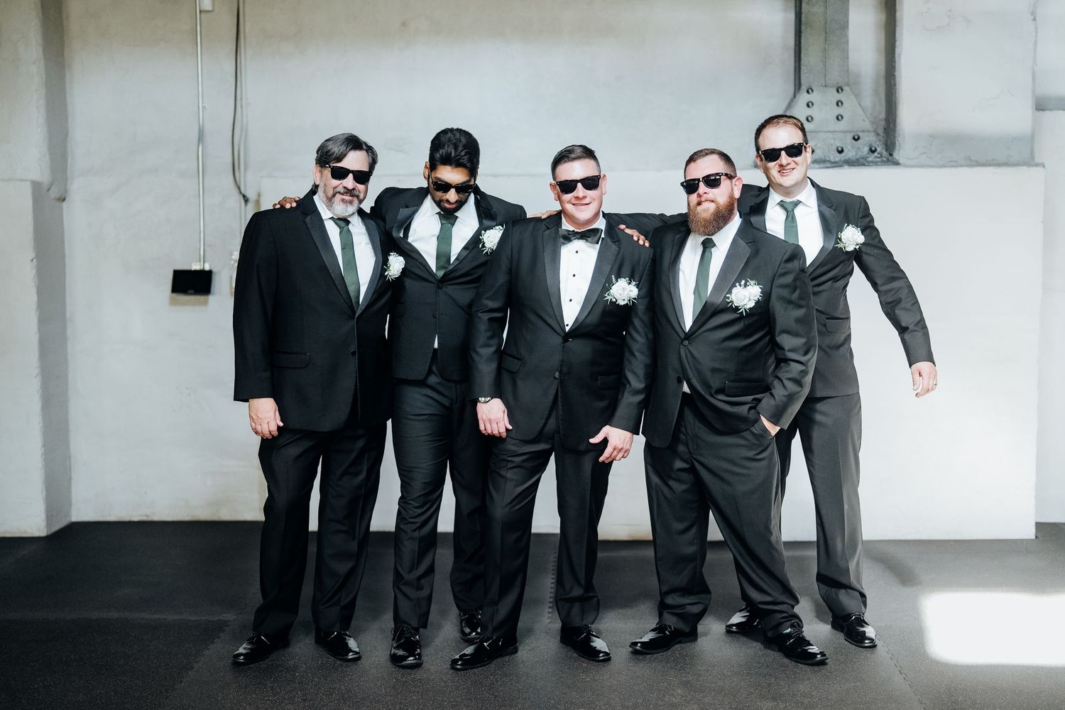 Wedding party in black suits and sunglasses striking cool poses together.
