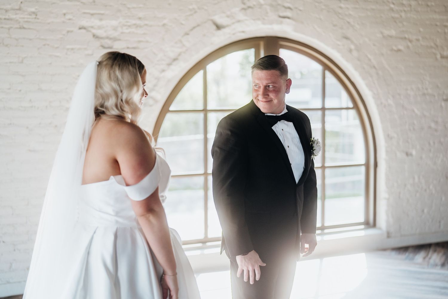 First look wedding photos being taken in front of arched windows.