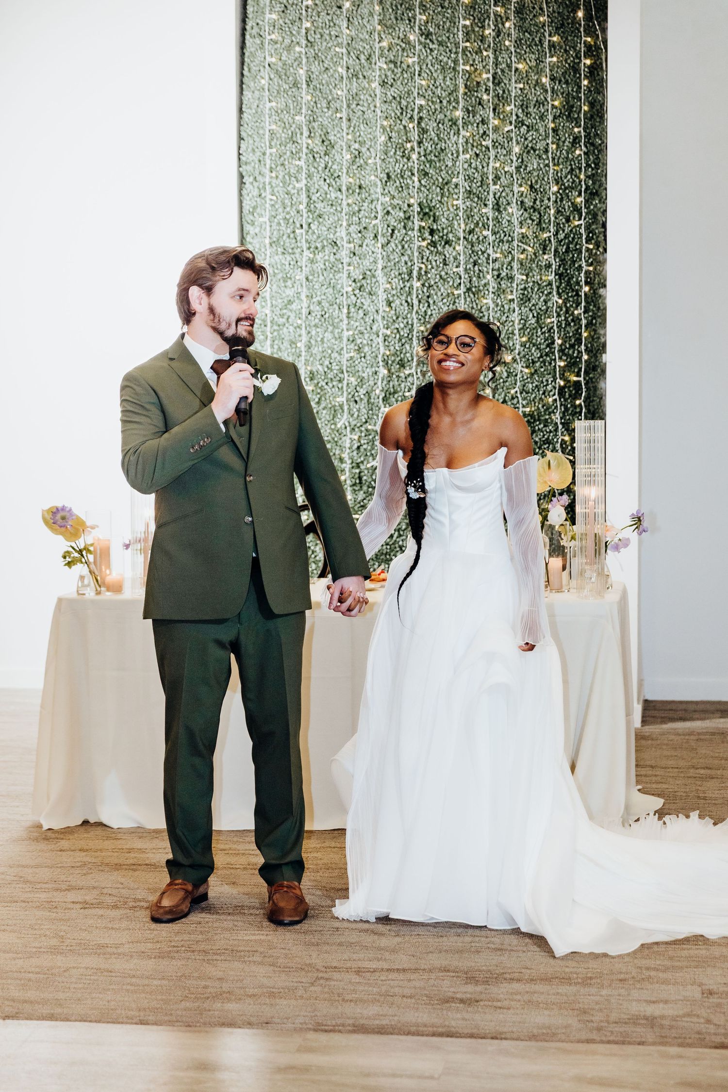 Newlyweds share their first dance in an elegant reception venue with sparkly backdrop and white decor.