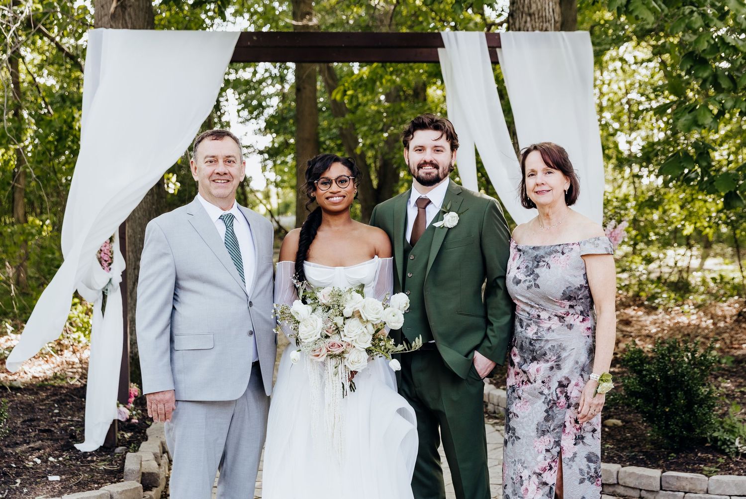Wedding party members pose together outdoors wearing coordinated formal attire.
