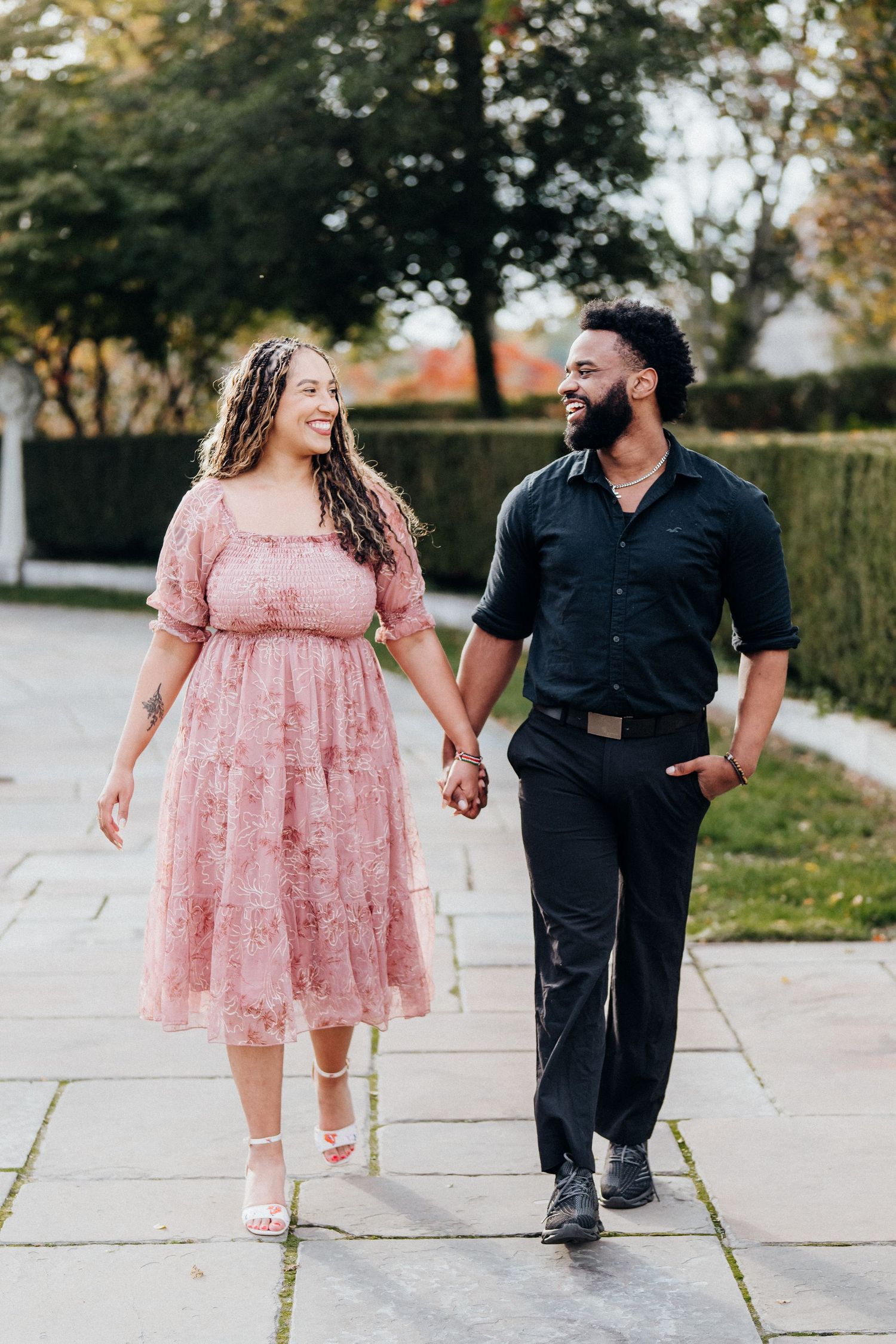 A couple walks together laughing on a stone pathway.