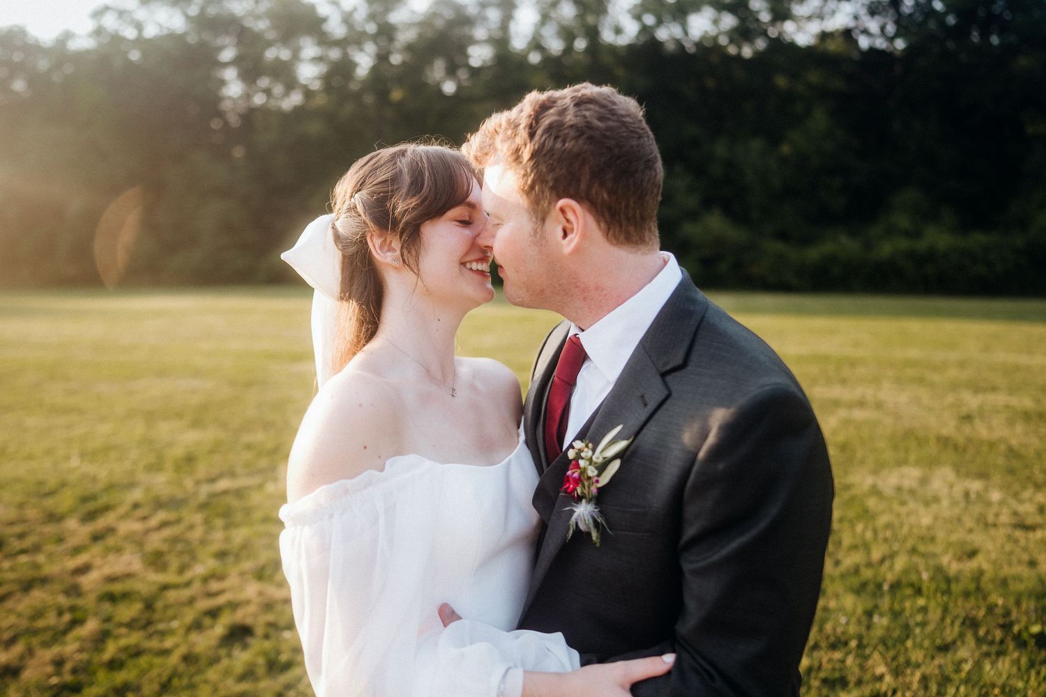 Intimate wedding portrait during golden hour in grassy field.