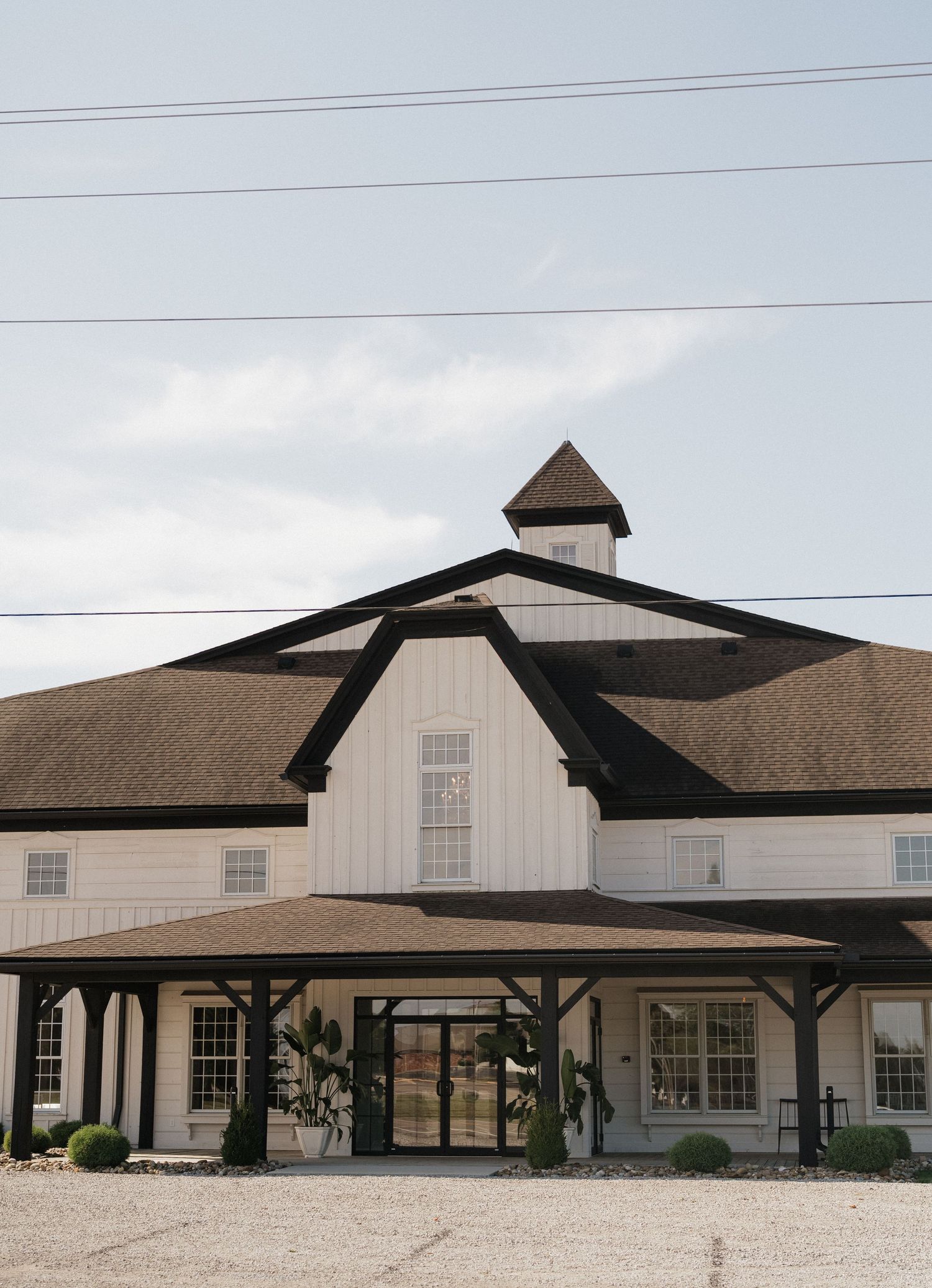 Modern white barn venue with black trim and architectural details shown from multiple exterior angles.