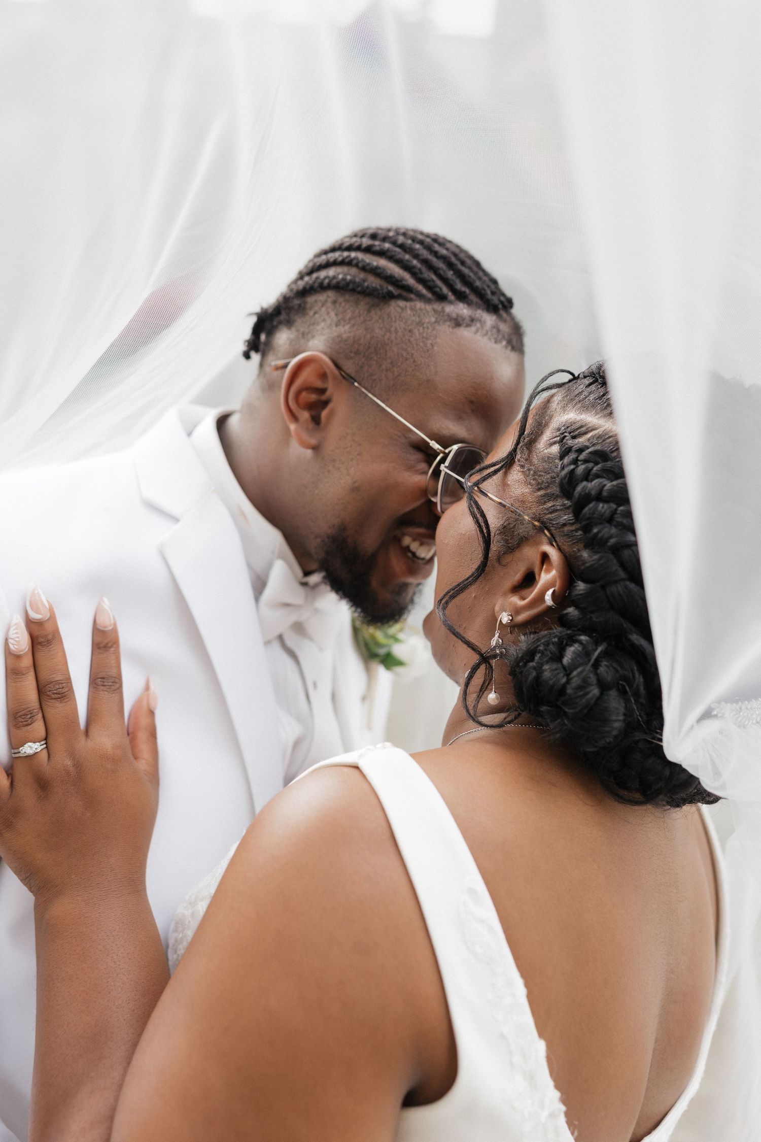 An intimate wedding portrait moment against a white backdrop with elegant attire.