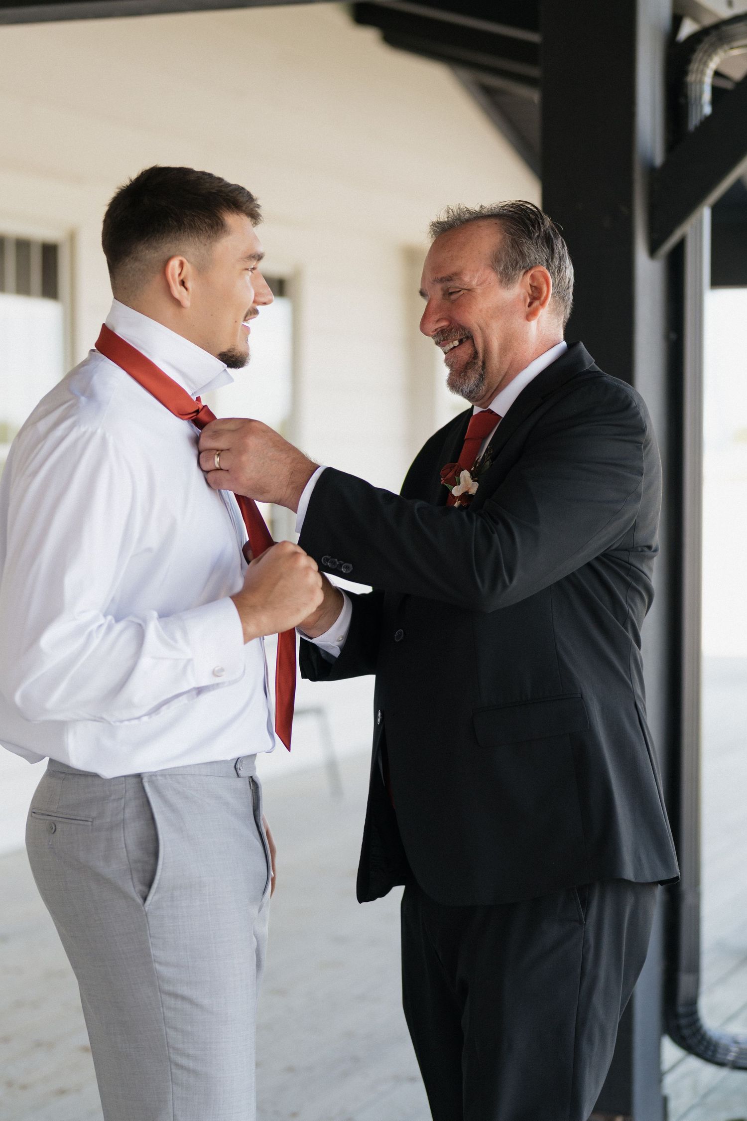 Groomsmen in black and light gray suits share a candid moment during pre-wedding preparations.