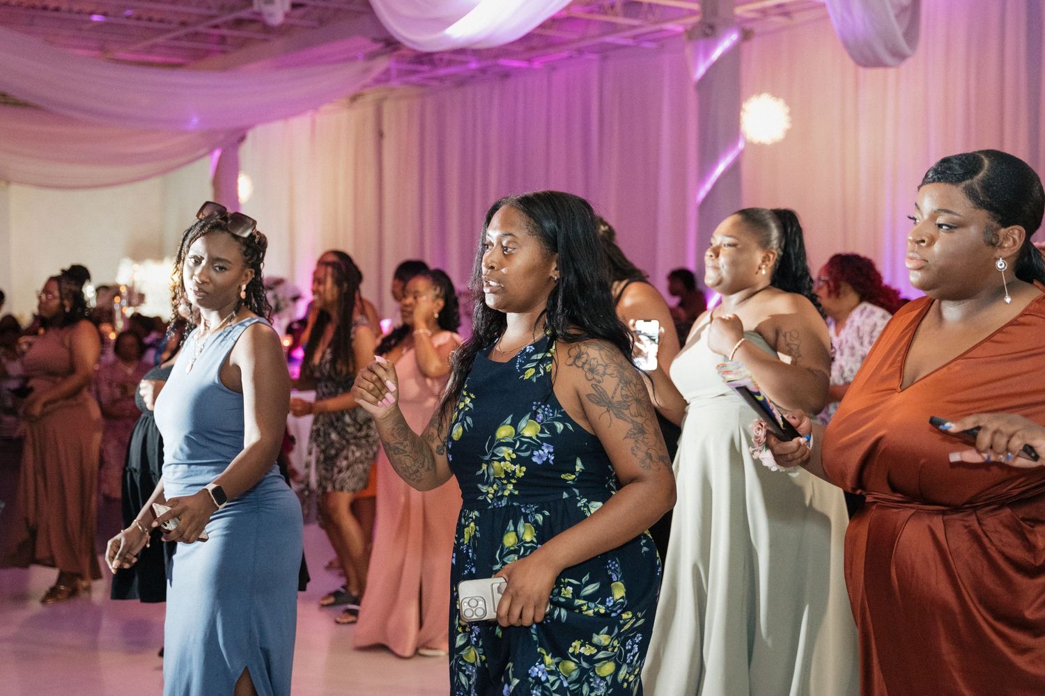 Wedding reception dance floor filled with guests enjoying the celebration under purple lighting.
