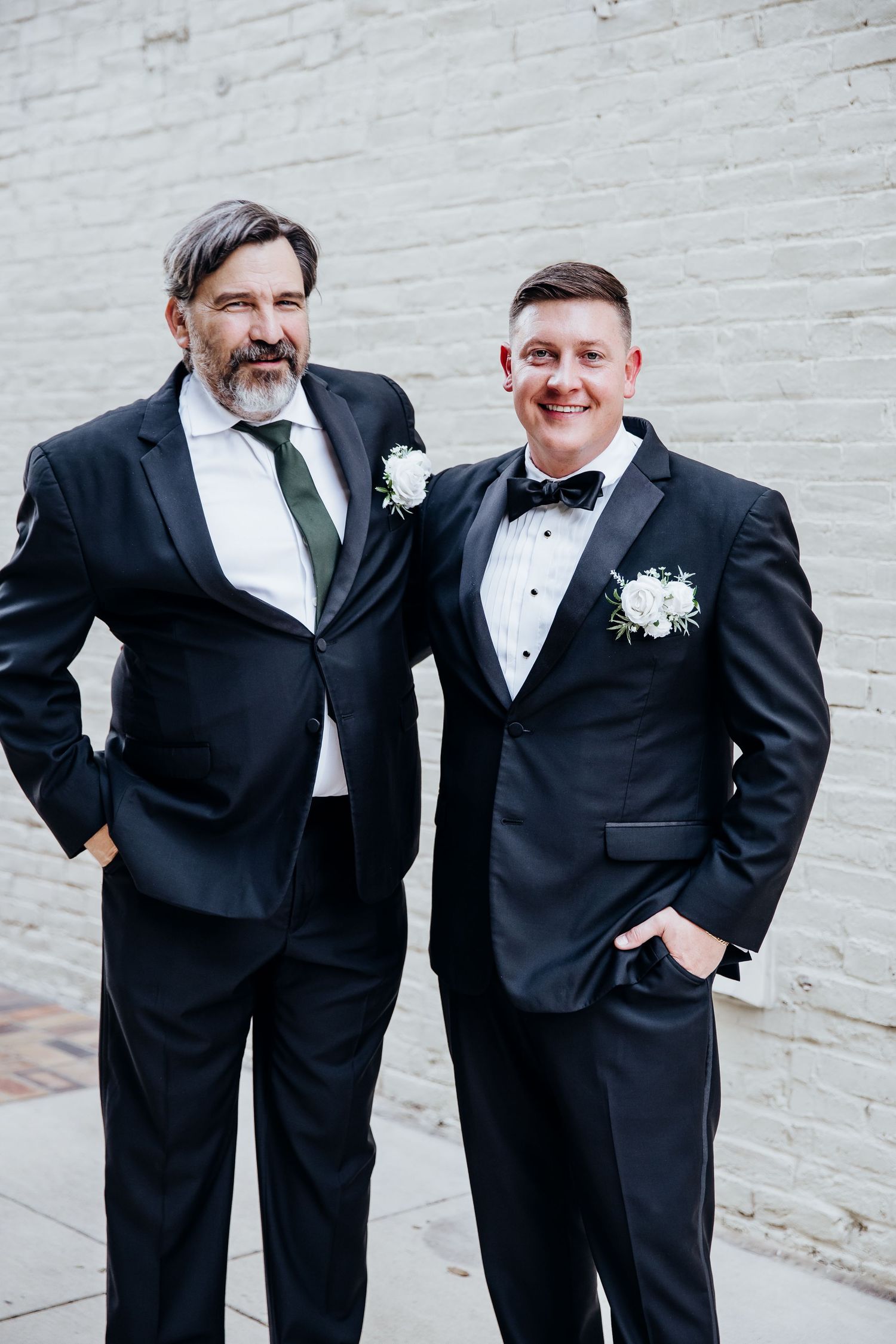 Groomsmen in classic tuxedos share candid moments before the wedding ceremony.