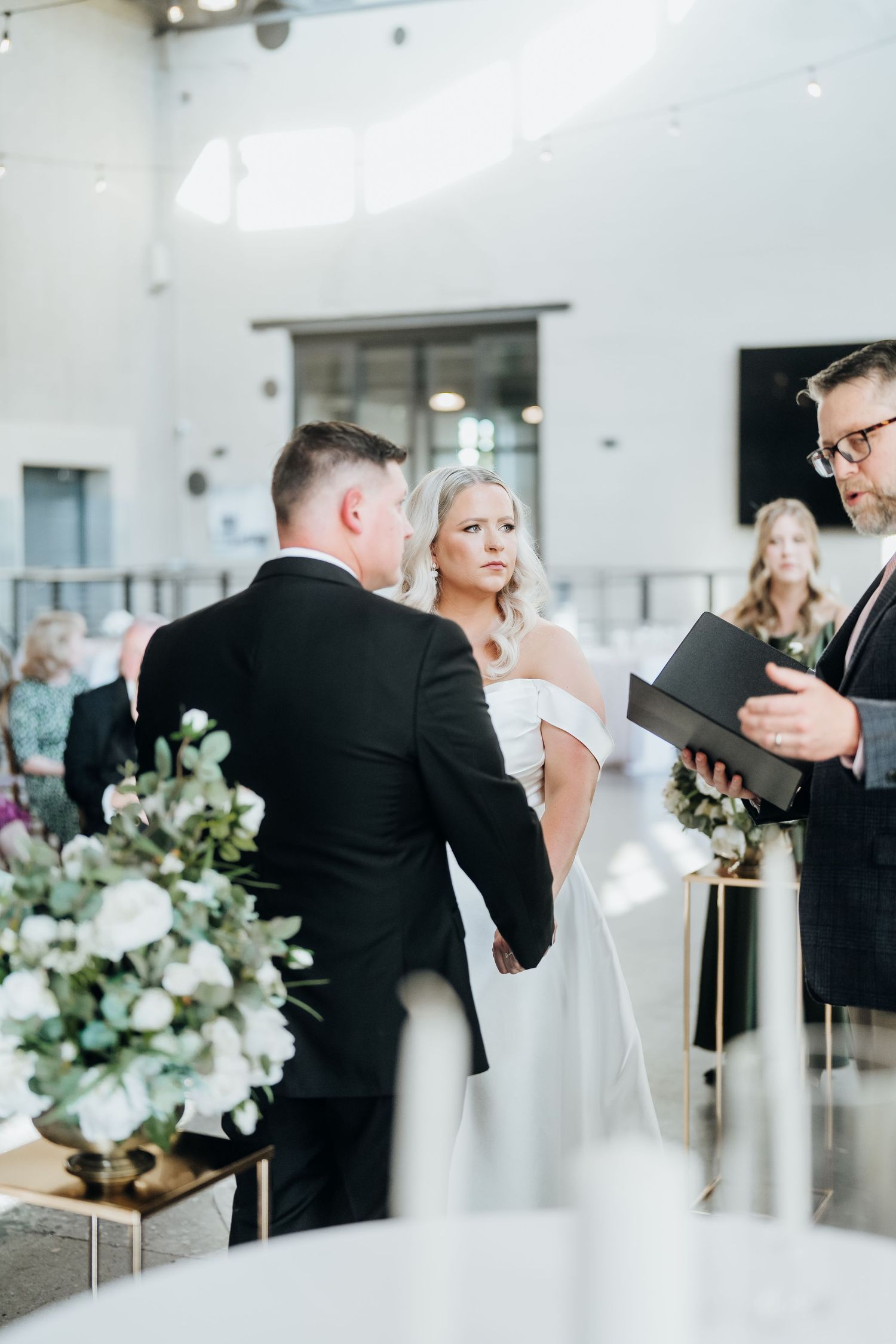 Modern wedding ceremony in a bright white venue with elegant floral arrangements.