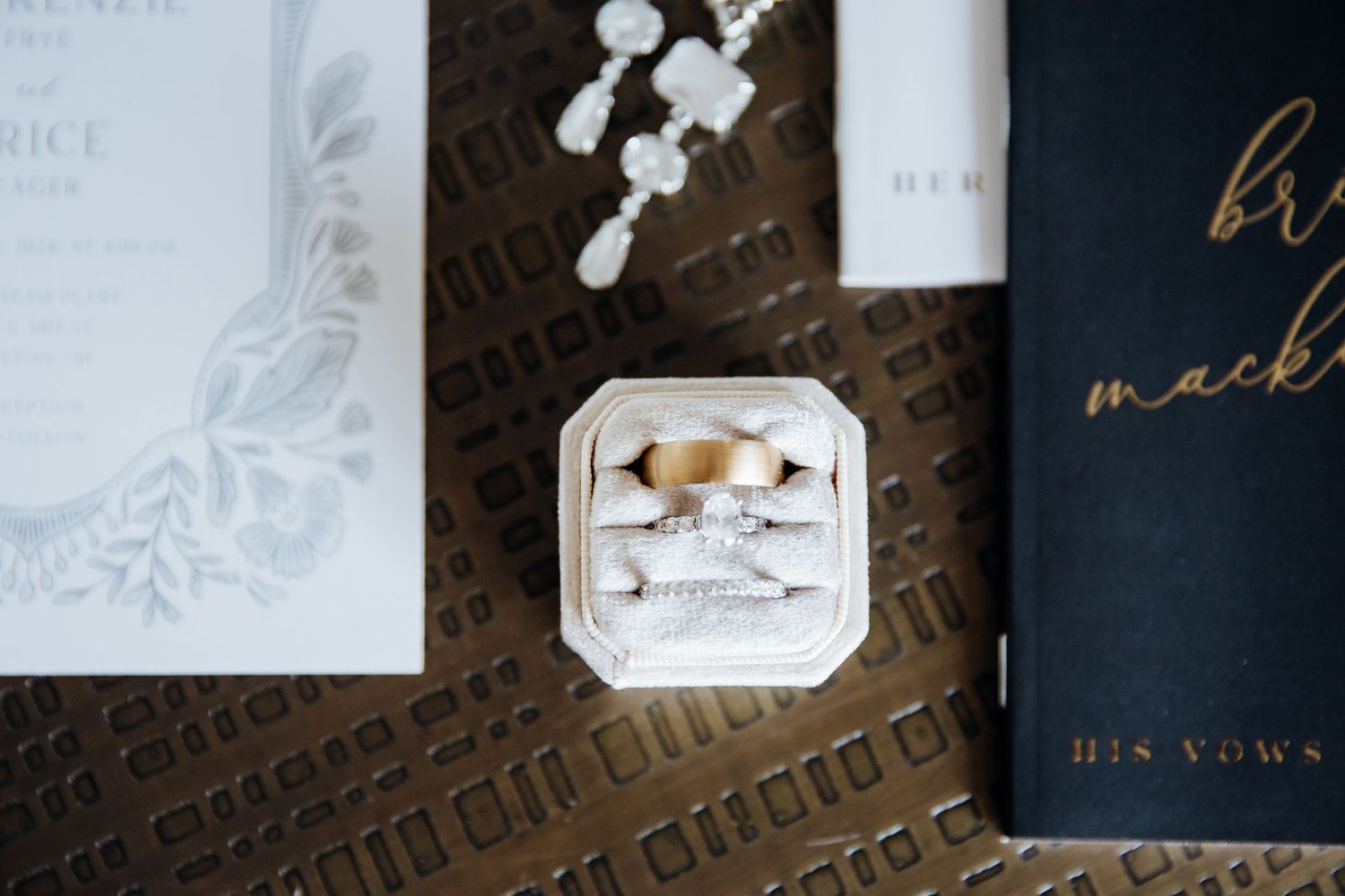 Elegant black and white wedding stationery with gold accents and floral details arranged on dark surface.