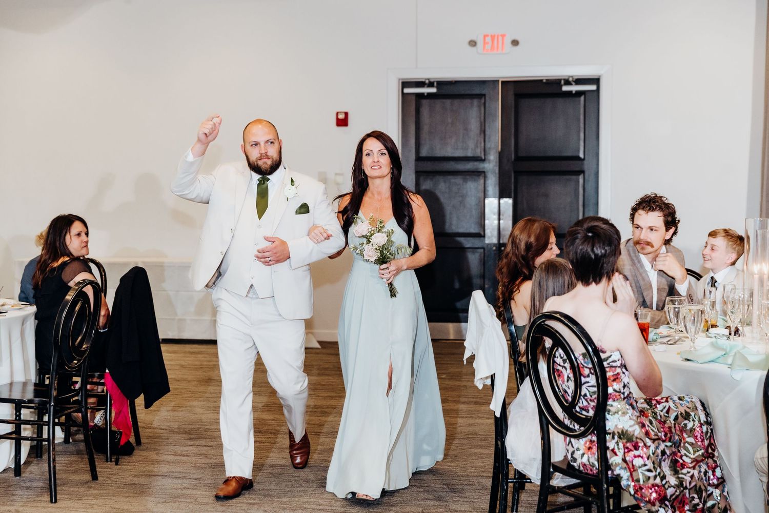 Wedding reception venue with guests mingling under string lights and chandeliers.