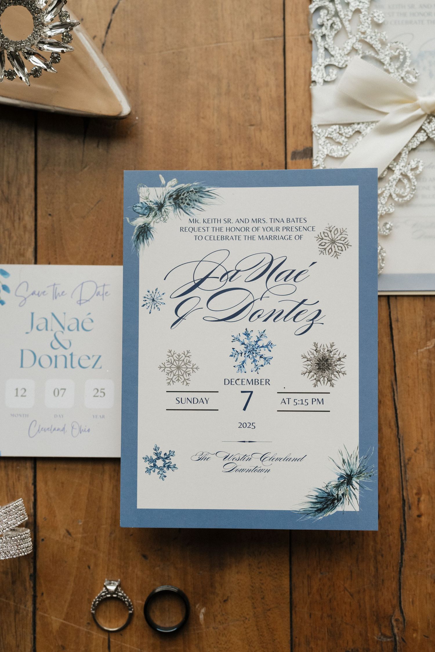 Wedding invitation cards with blue snowflake designs and elegant calligraphy displayed on a rustic wooden surface.