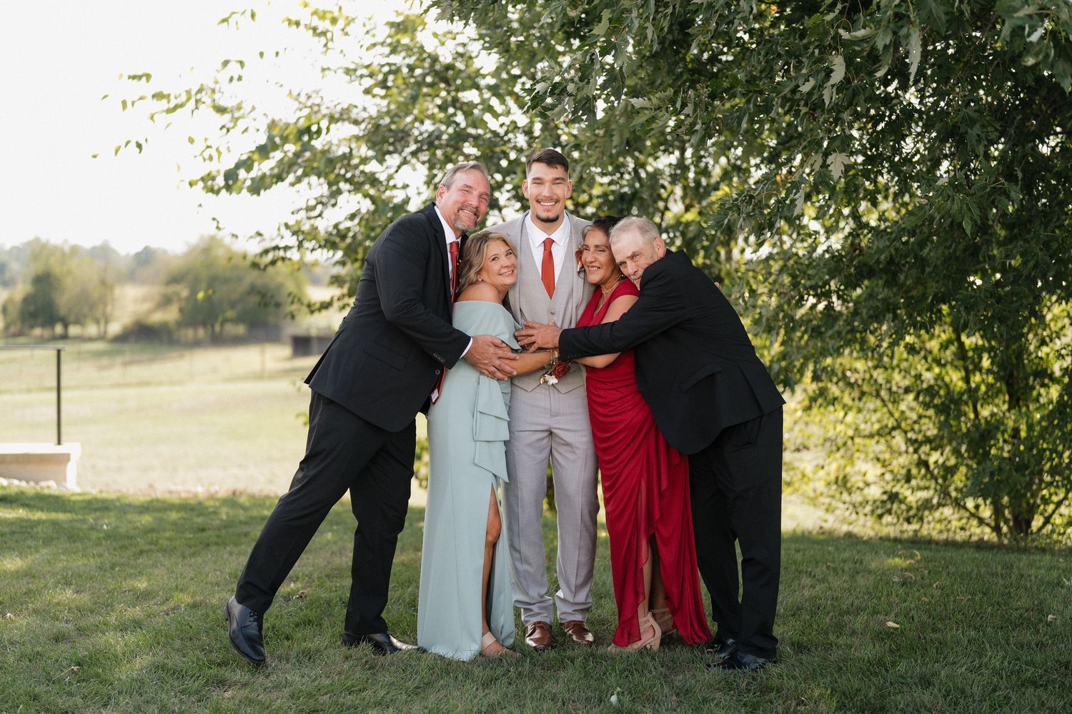 Wedding party poses for group photos in an outdoor garden setting.