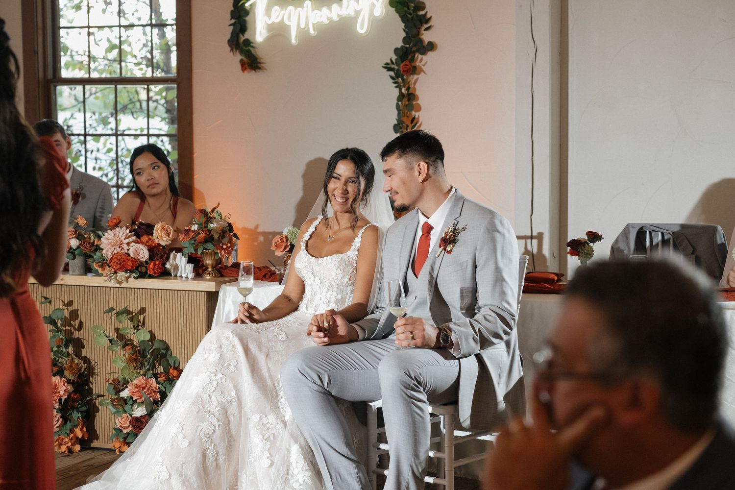 Indoor wedding reception space decorated with greenery and warm lighting.
