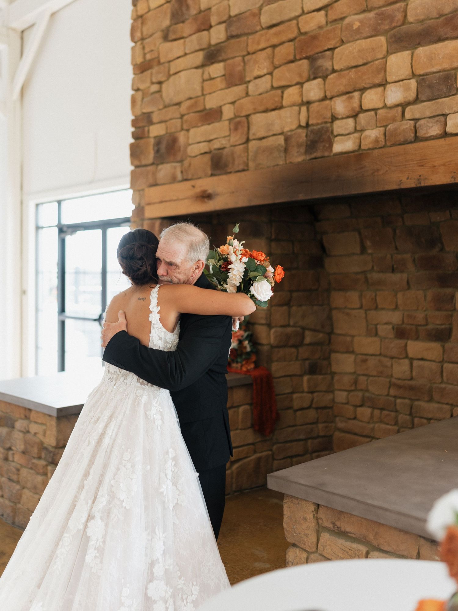 Wedding dress details shown against exposed brick wall background in rustic indoor setting.