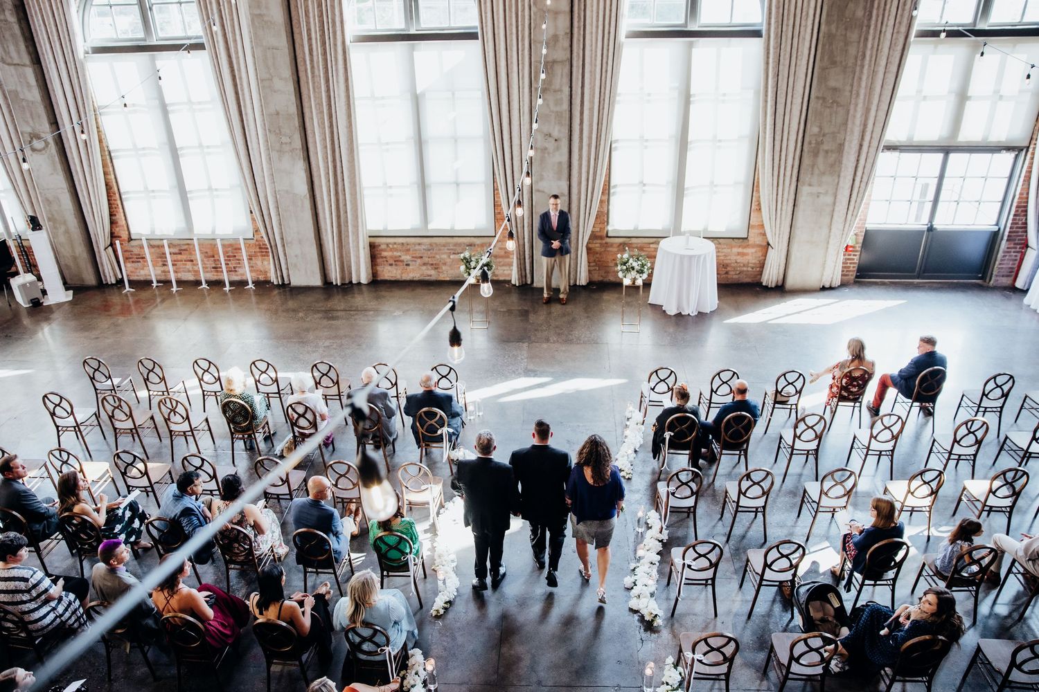 Overhead view of wedding ceremony setup with rows of white chairs in an industrial venue.