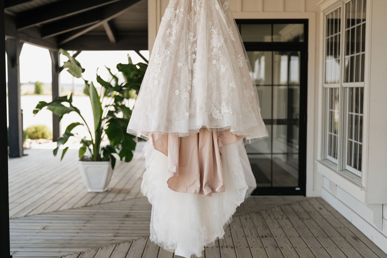 White wedding dresses hanging on display along a rustic wooden porch with white trim.