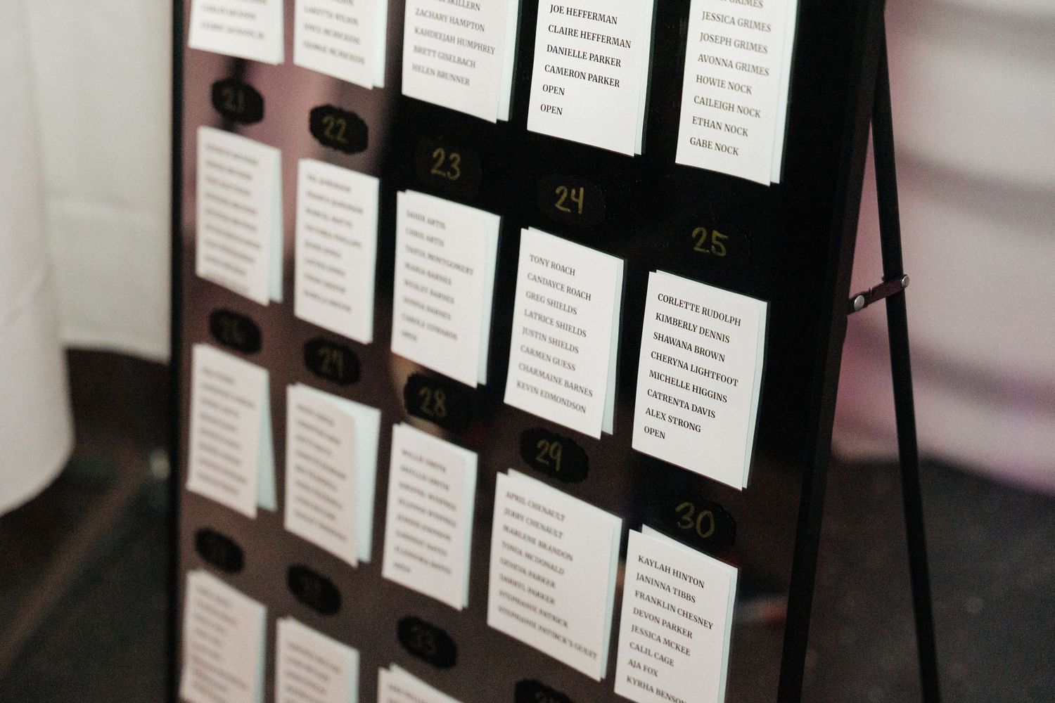 Detail shot of wedding seating chart with numbered table assignments in black display board.