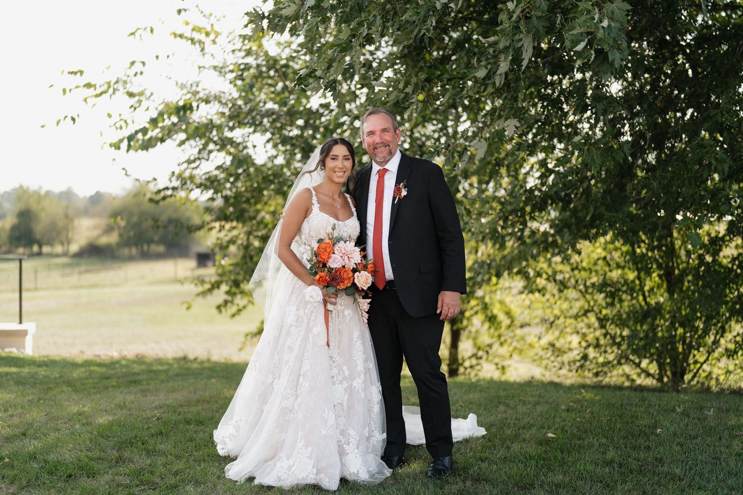 Wedding party members gather under trees for formal outdoor portraits.