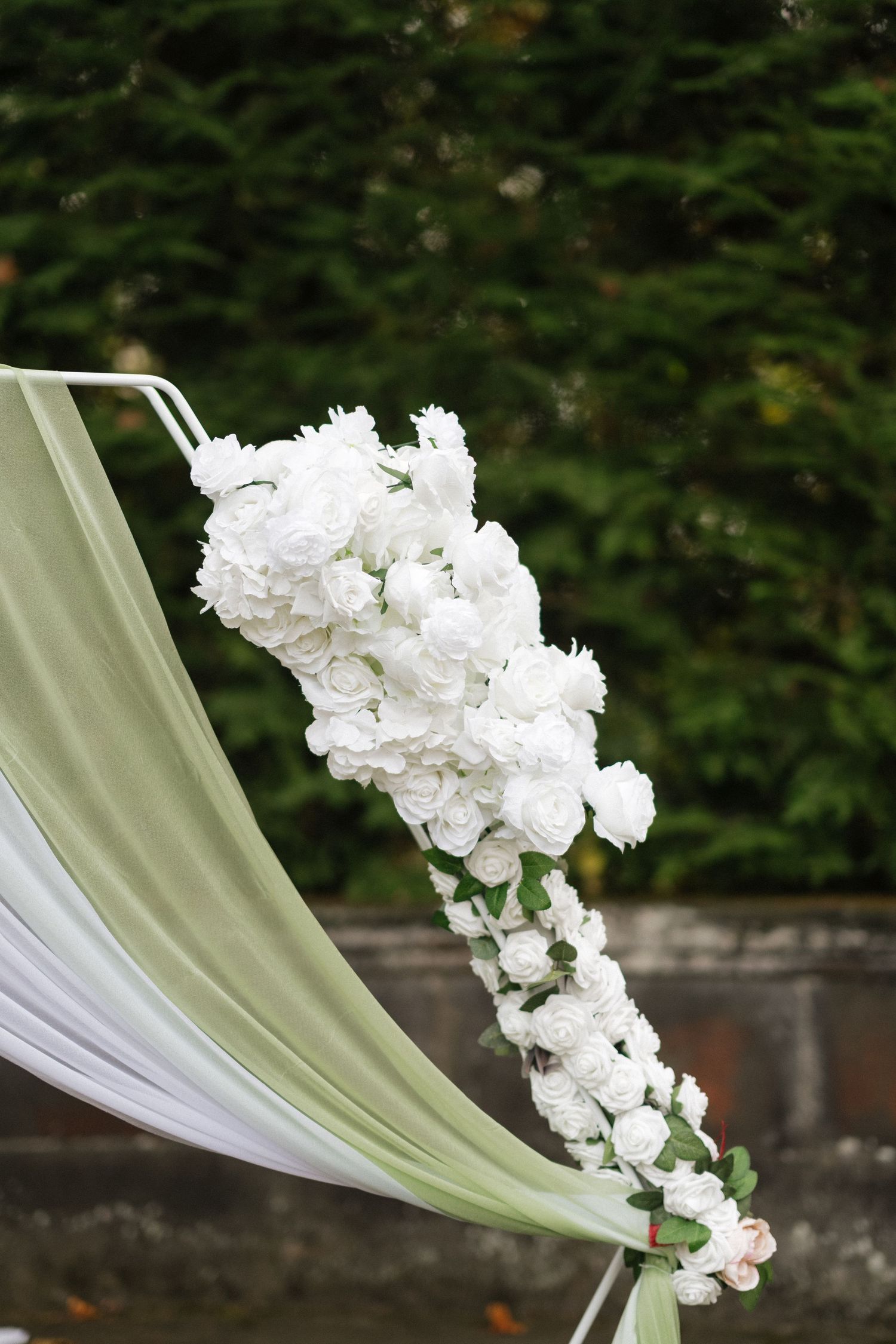White floral decorations and draped fabric create an elegant outdoor wedding setting.