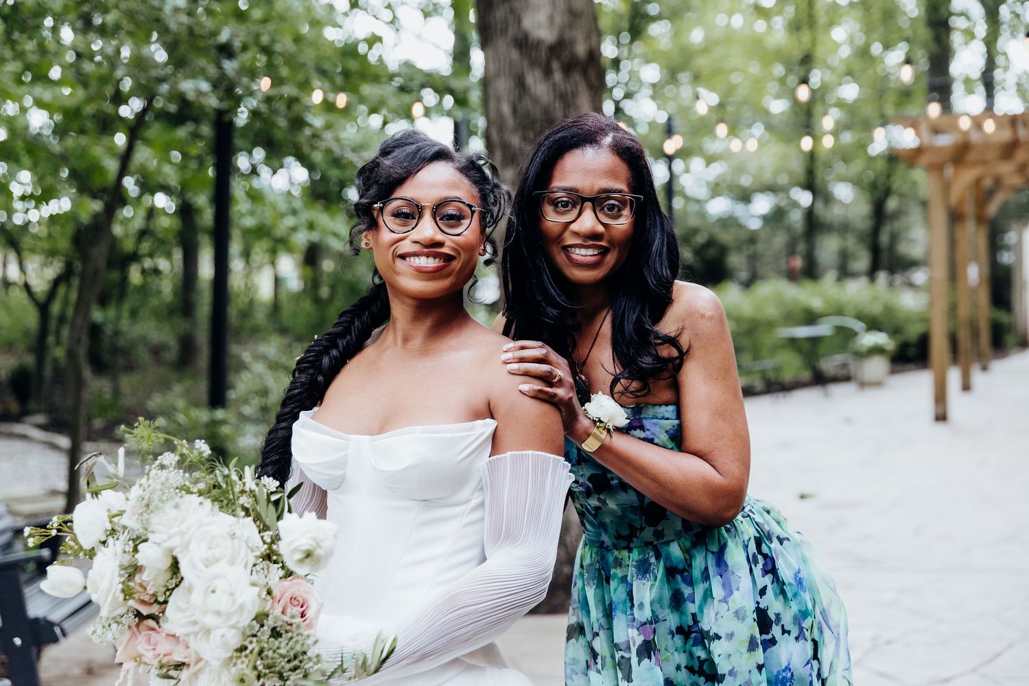 Wedding party members in mint green dresses gather for photos in an outdoor garden setting.
