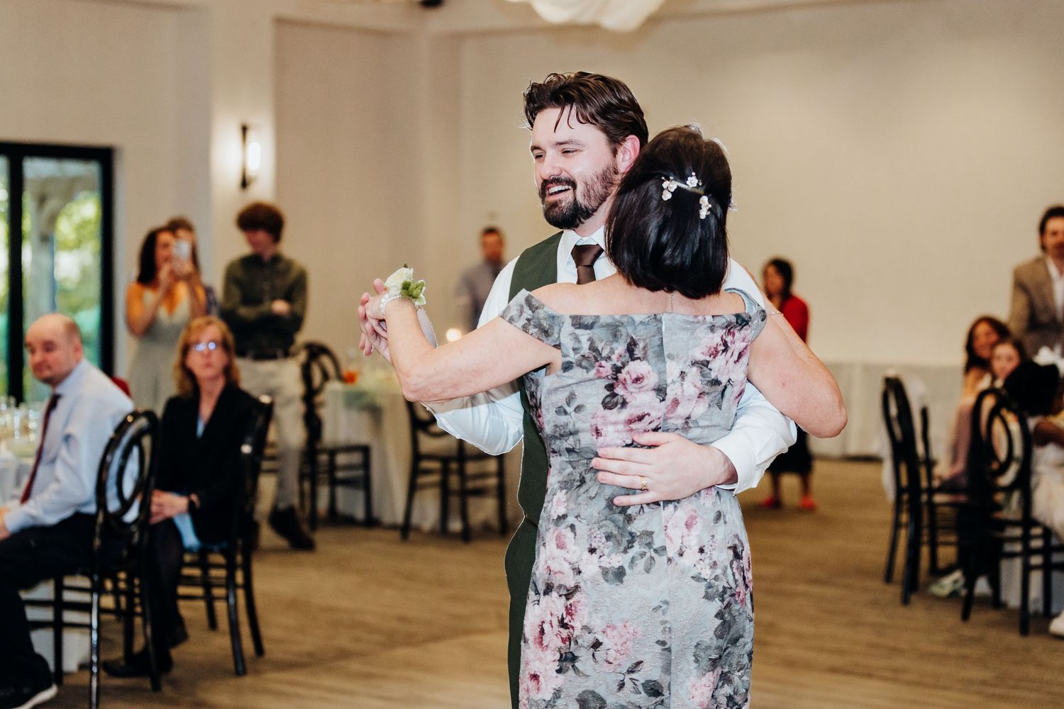 Wedding guests dance and celebrate in elegant indoor reception venue.