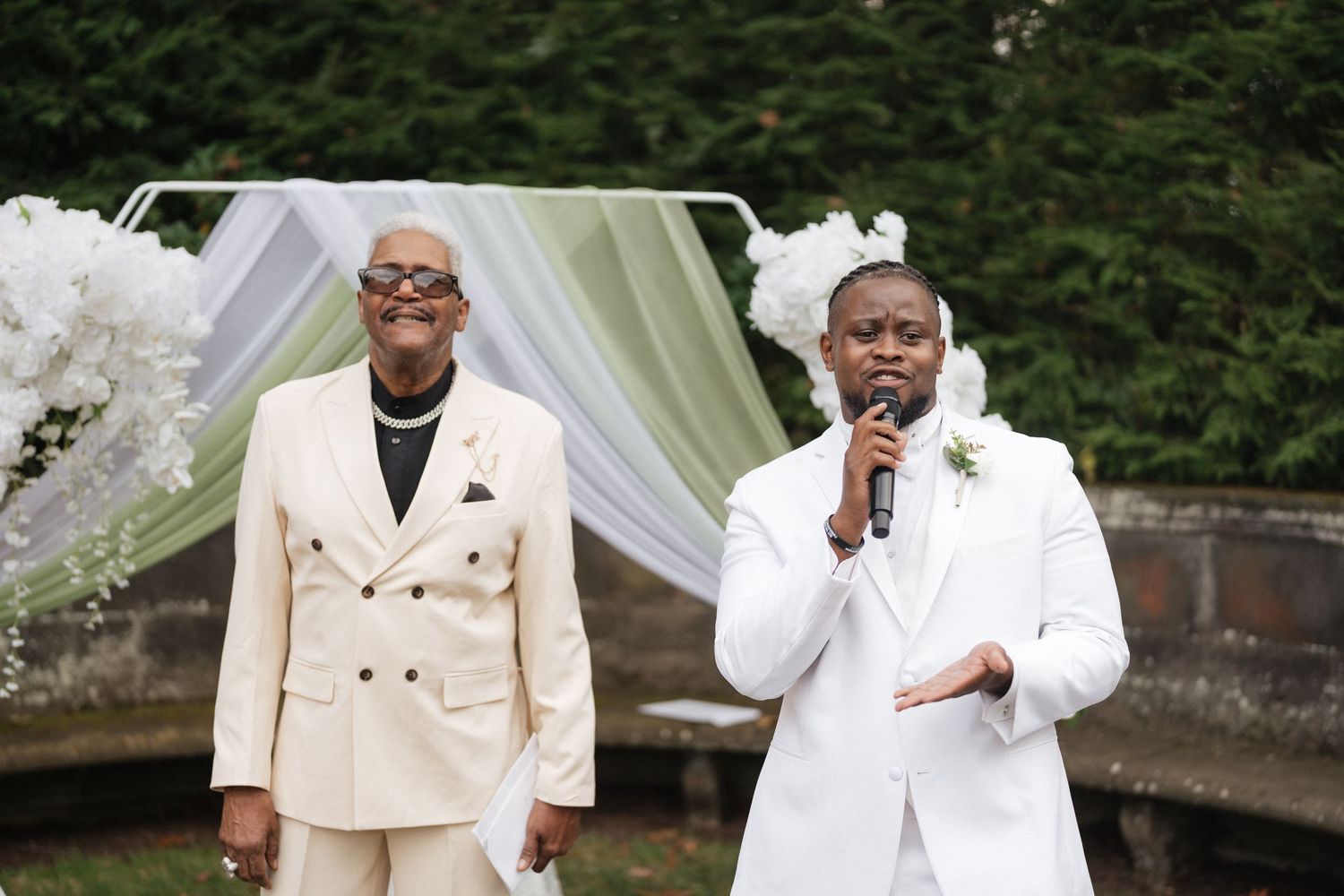 Wedding party members in elegant cream suits gather for formal photos.