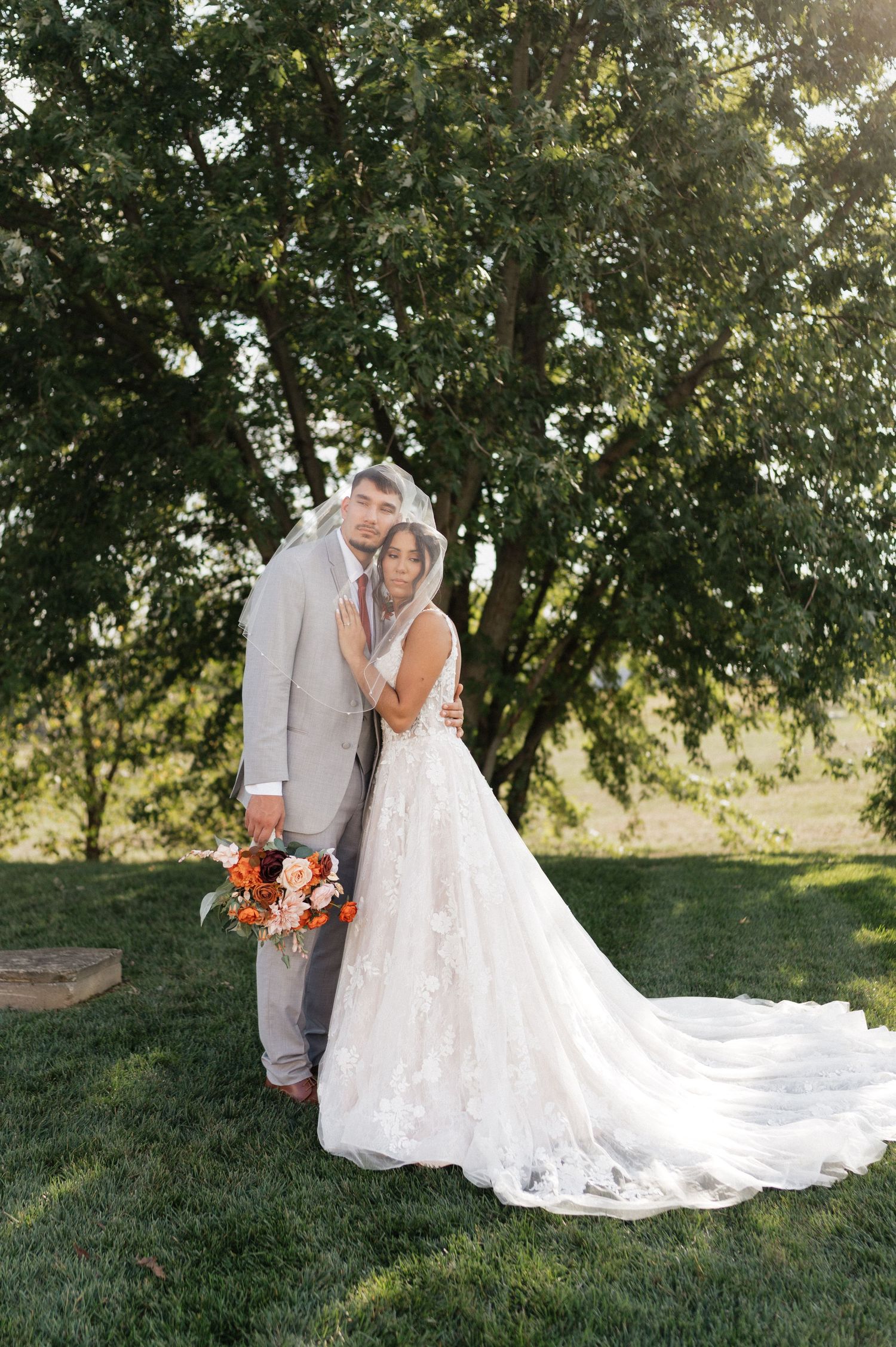 Couple shares intimate moment during sunset wedding photos with flowing white dress train.