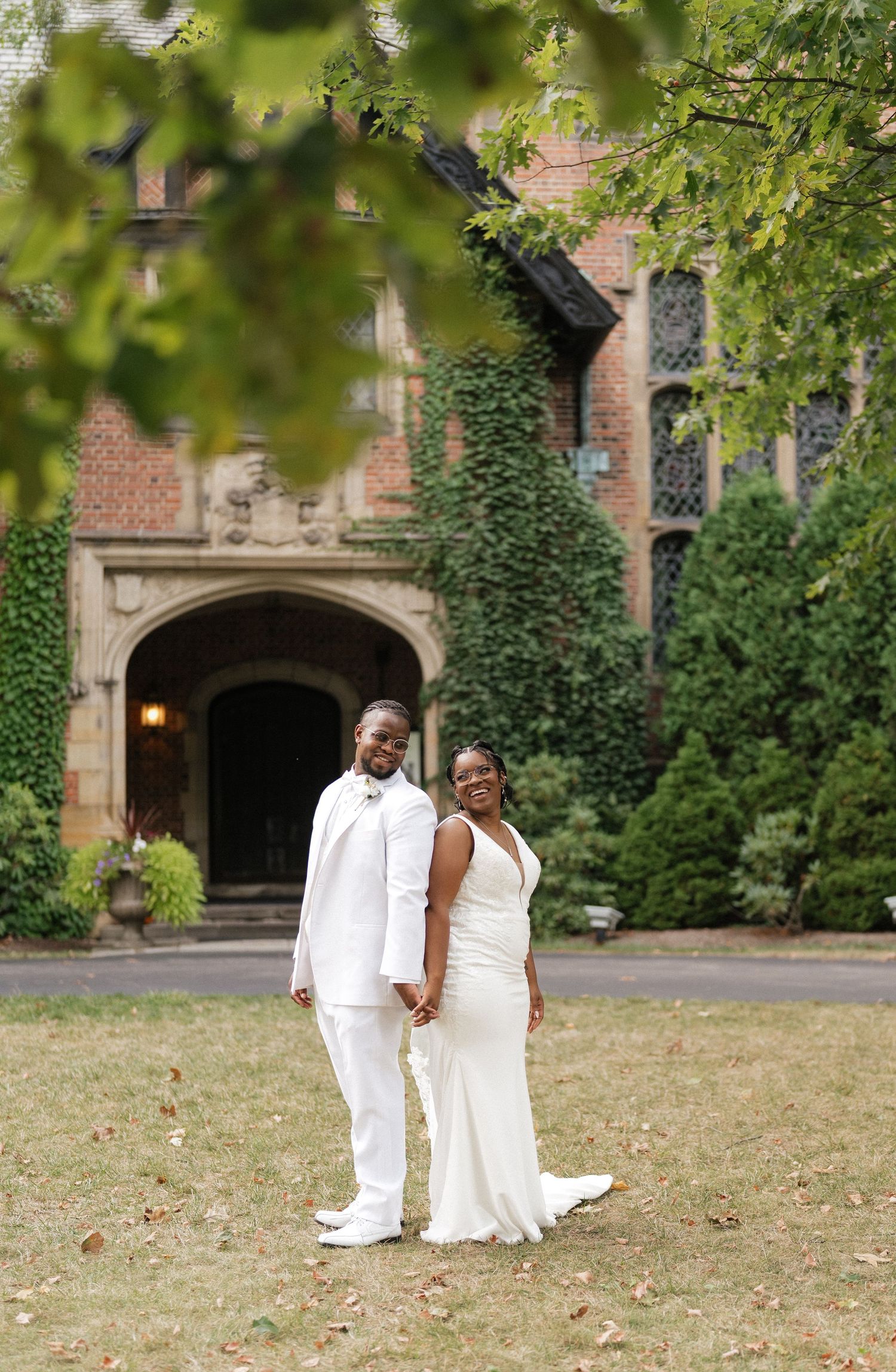 A romantic wedding photo session on a lush green lawn in front of a historic brick building.